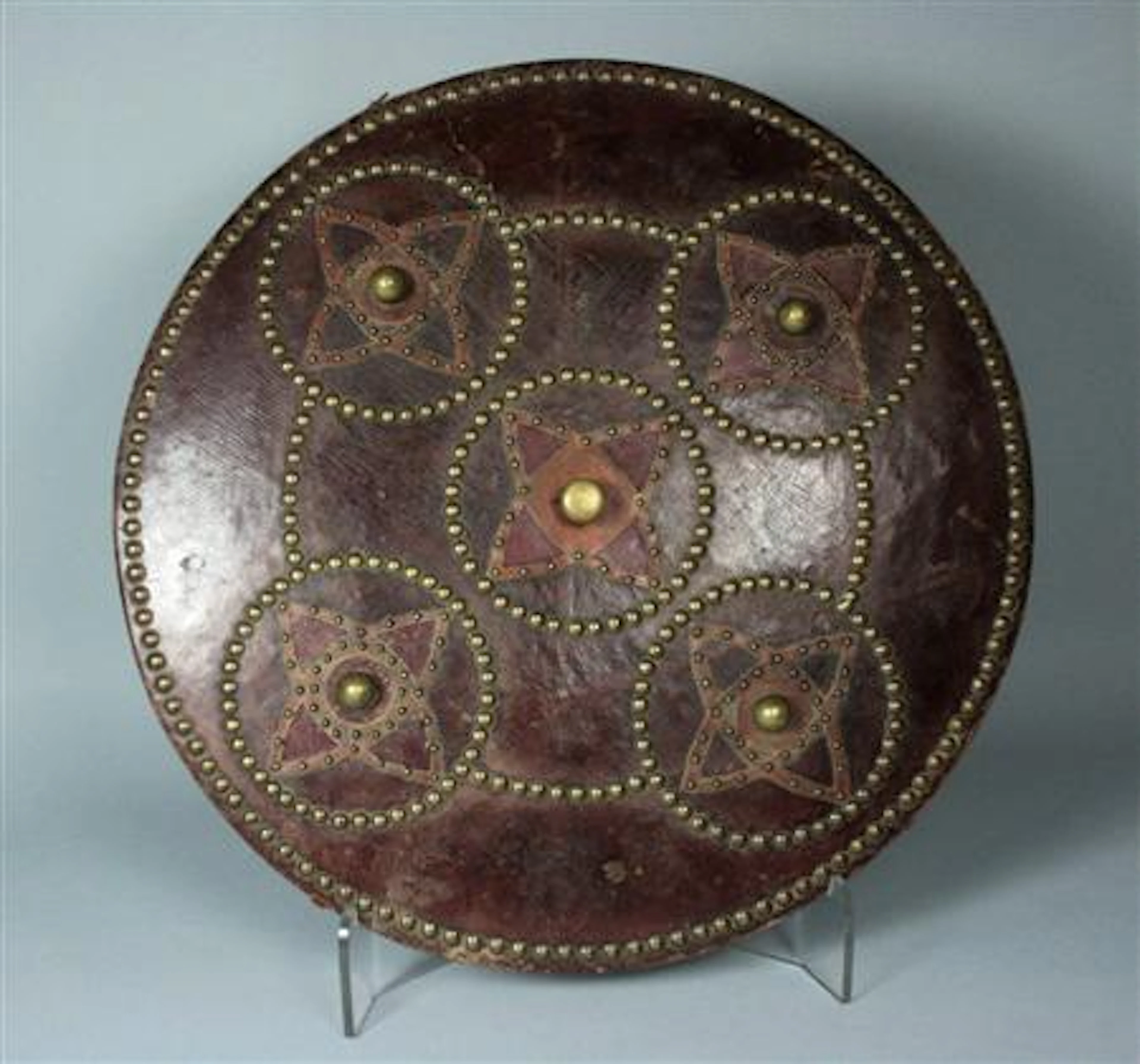 A reproduction Scottish targe, the leather covered wooden boards with leather and brass studded decoration, the central boss surrounded...