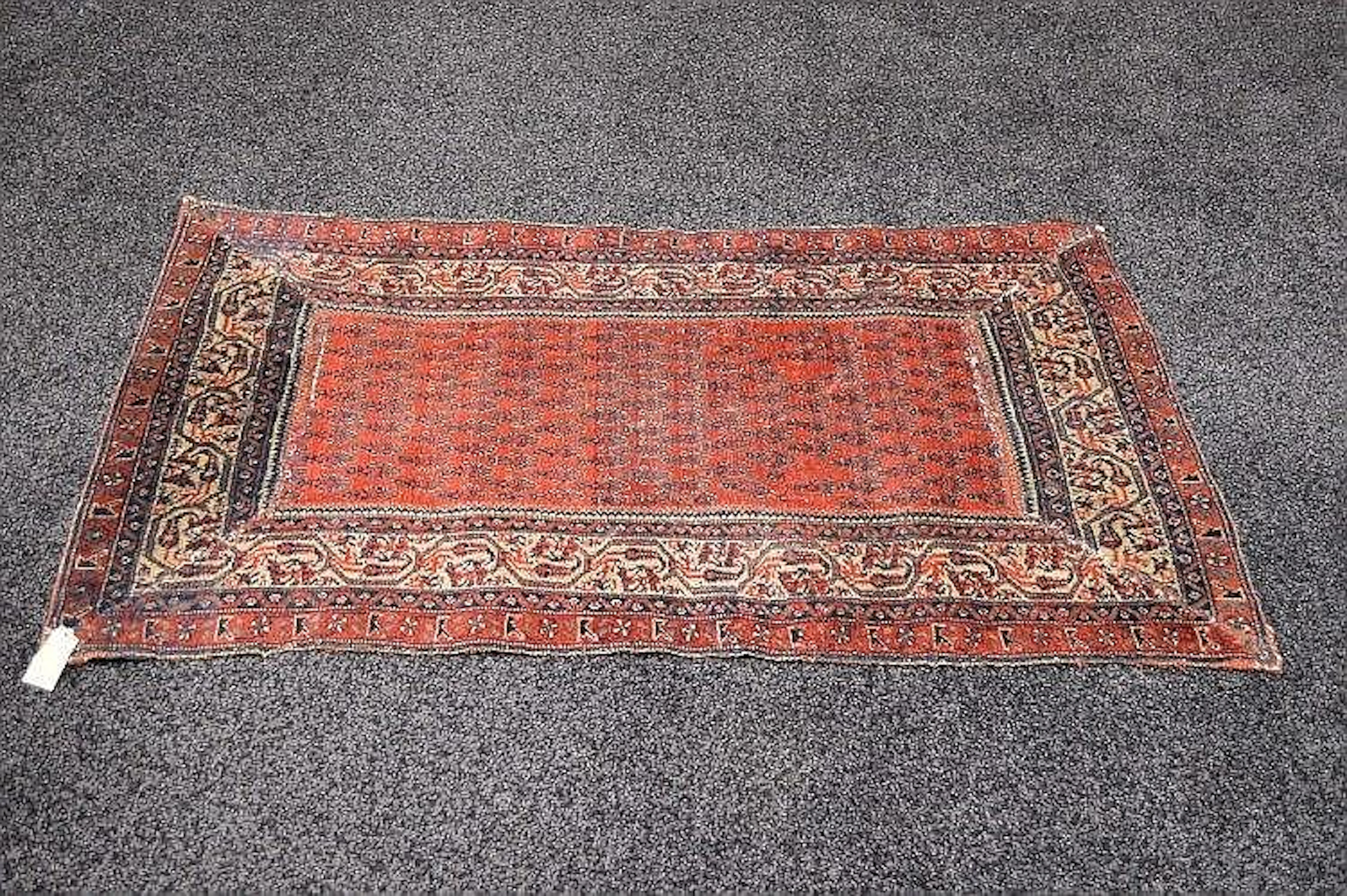 A red ground rug with blue and white pattern (both ends...