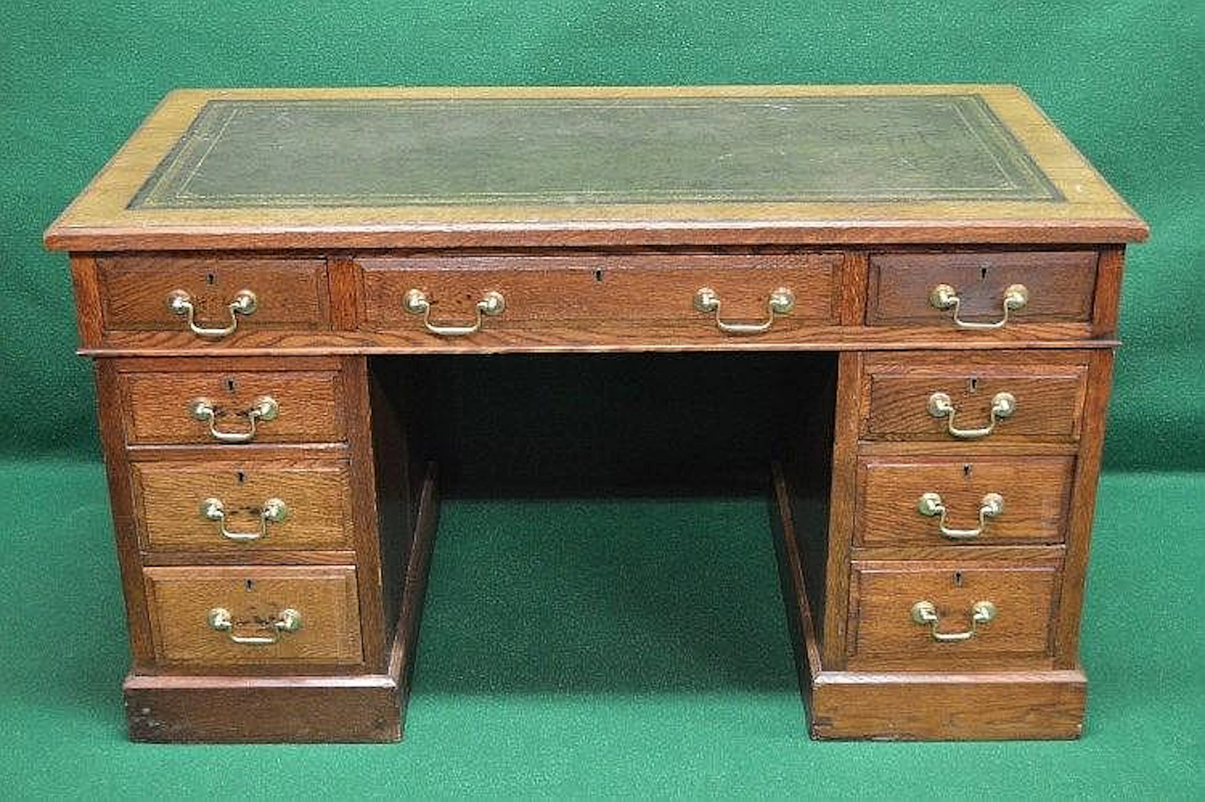 Oak pedestal desk with green leather insert over one long and two short drawers