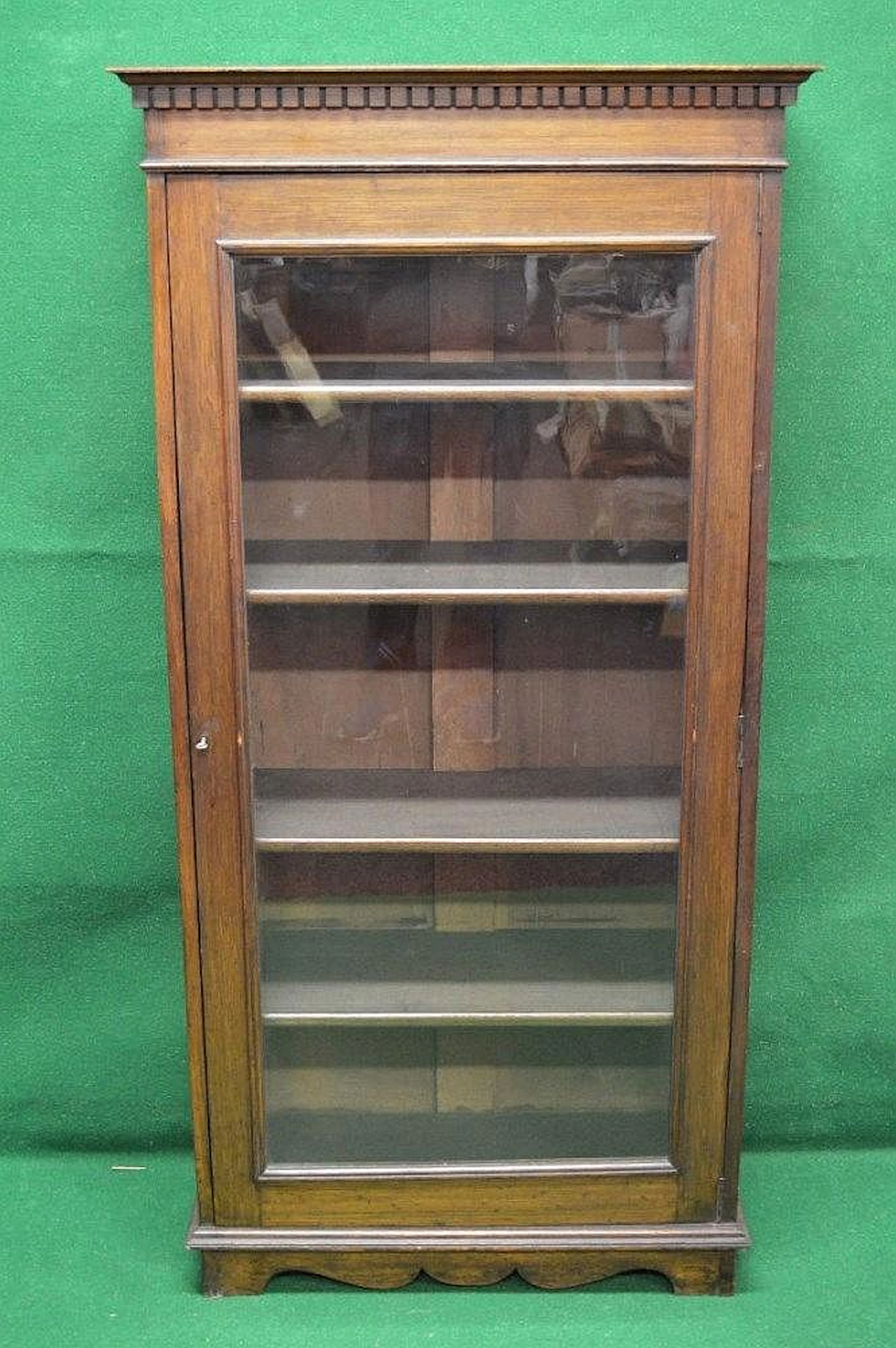 An oak glazed single door bookcase with dental cornice...