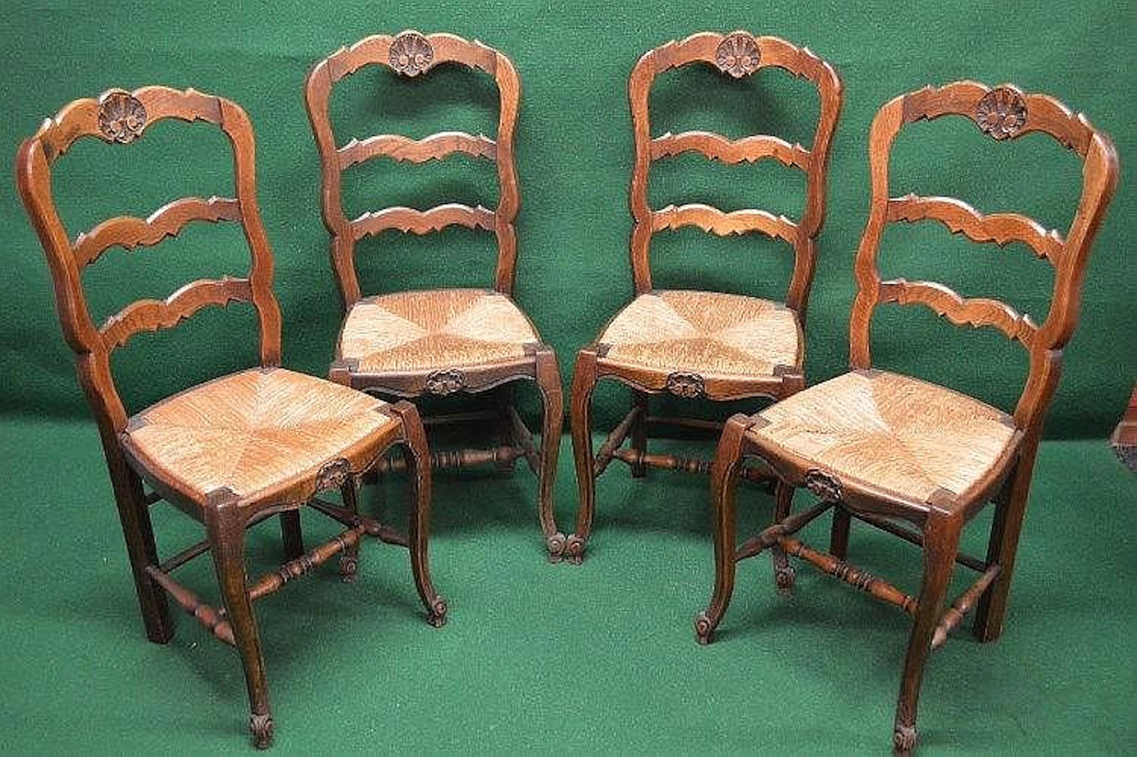 Set of four oak ladder back chairs with carved top rail...