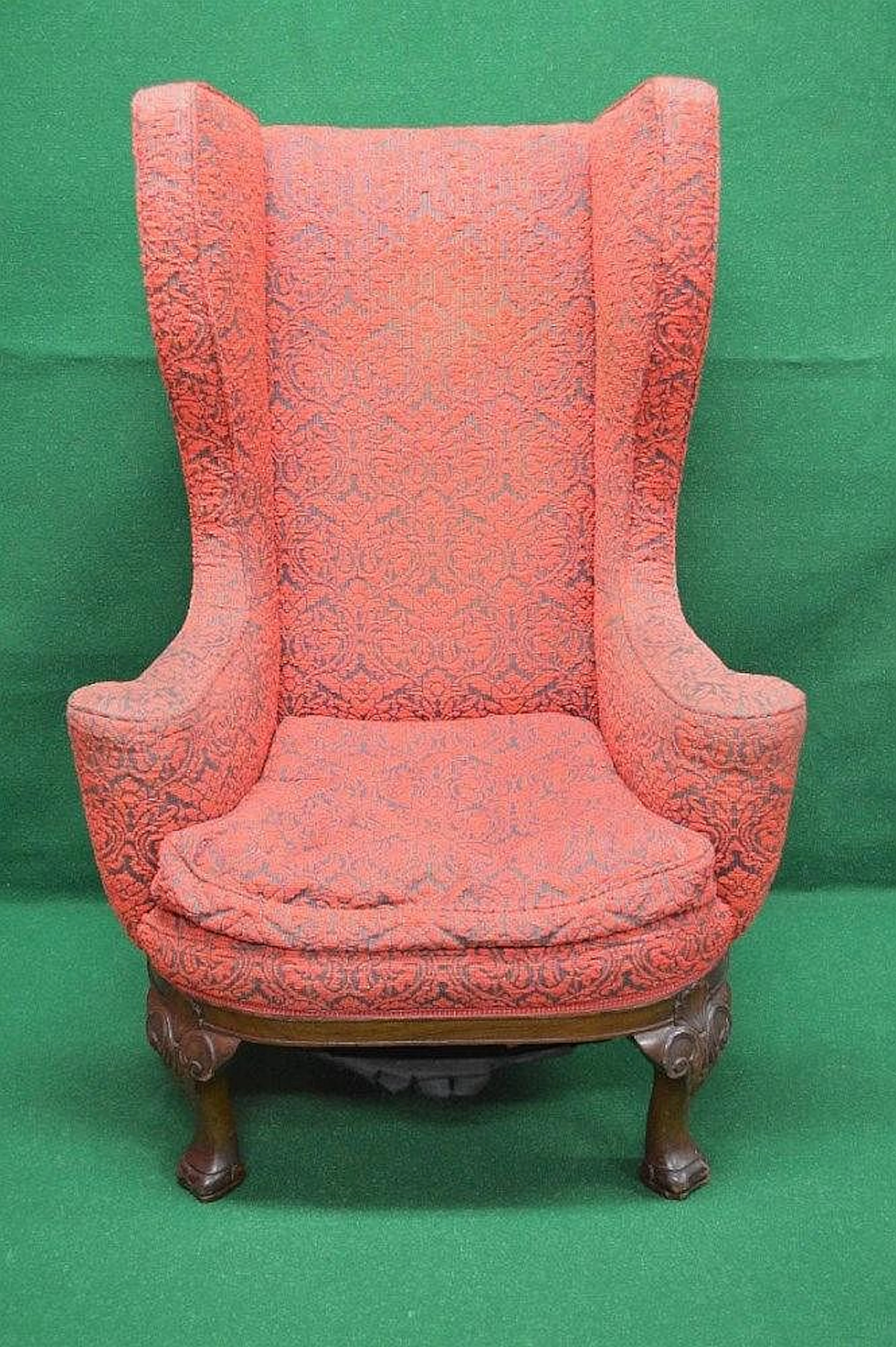 A high backed wing armchair having outward scrolled arms and removable cushion