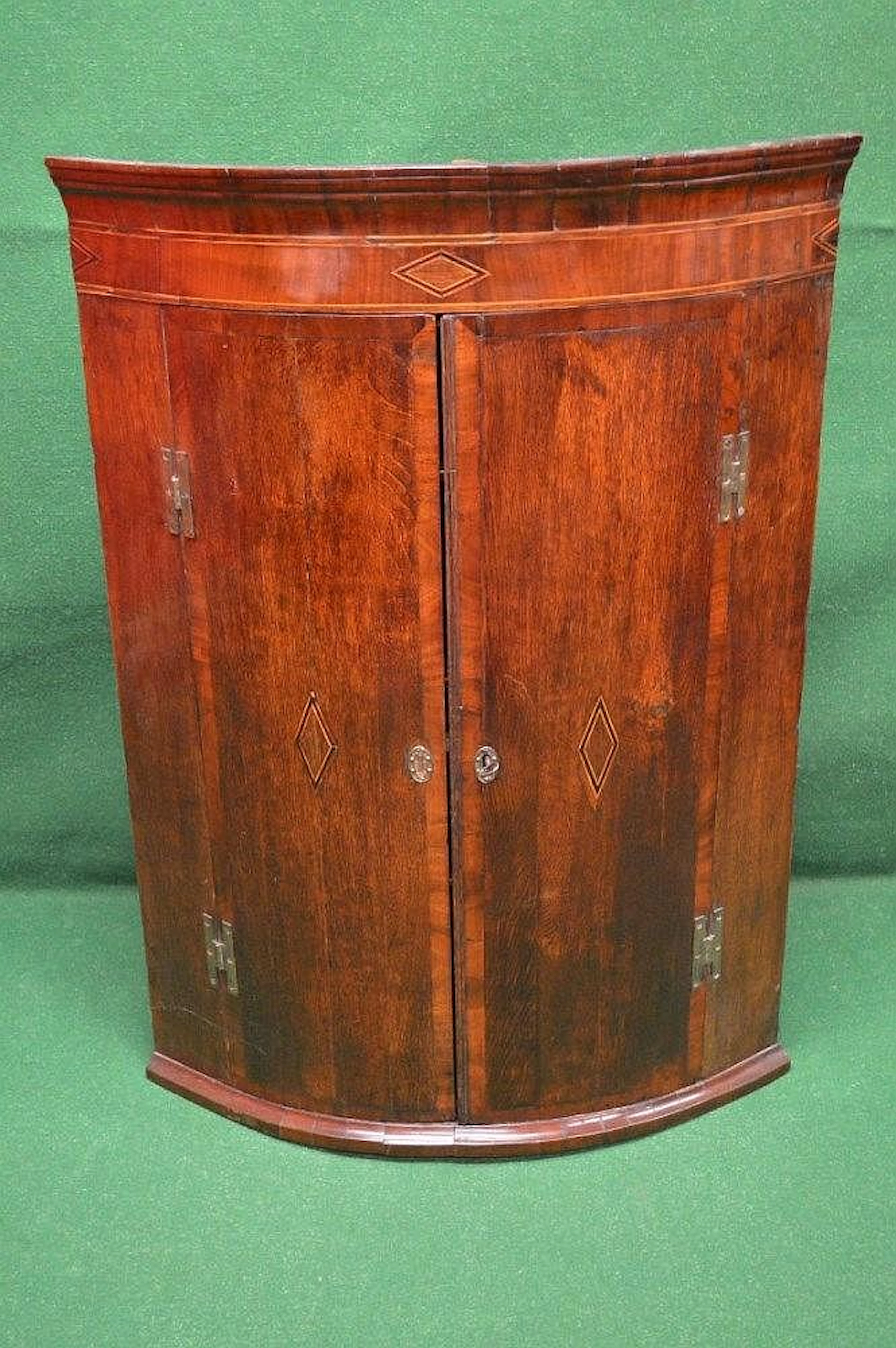 An oak inlaid wall hanging corner cupboard having two bow...