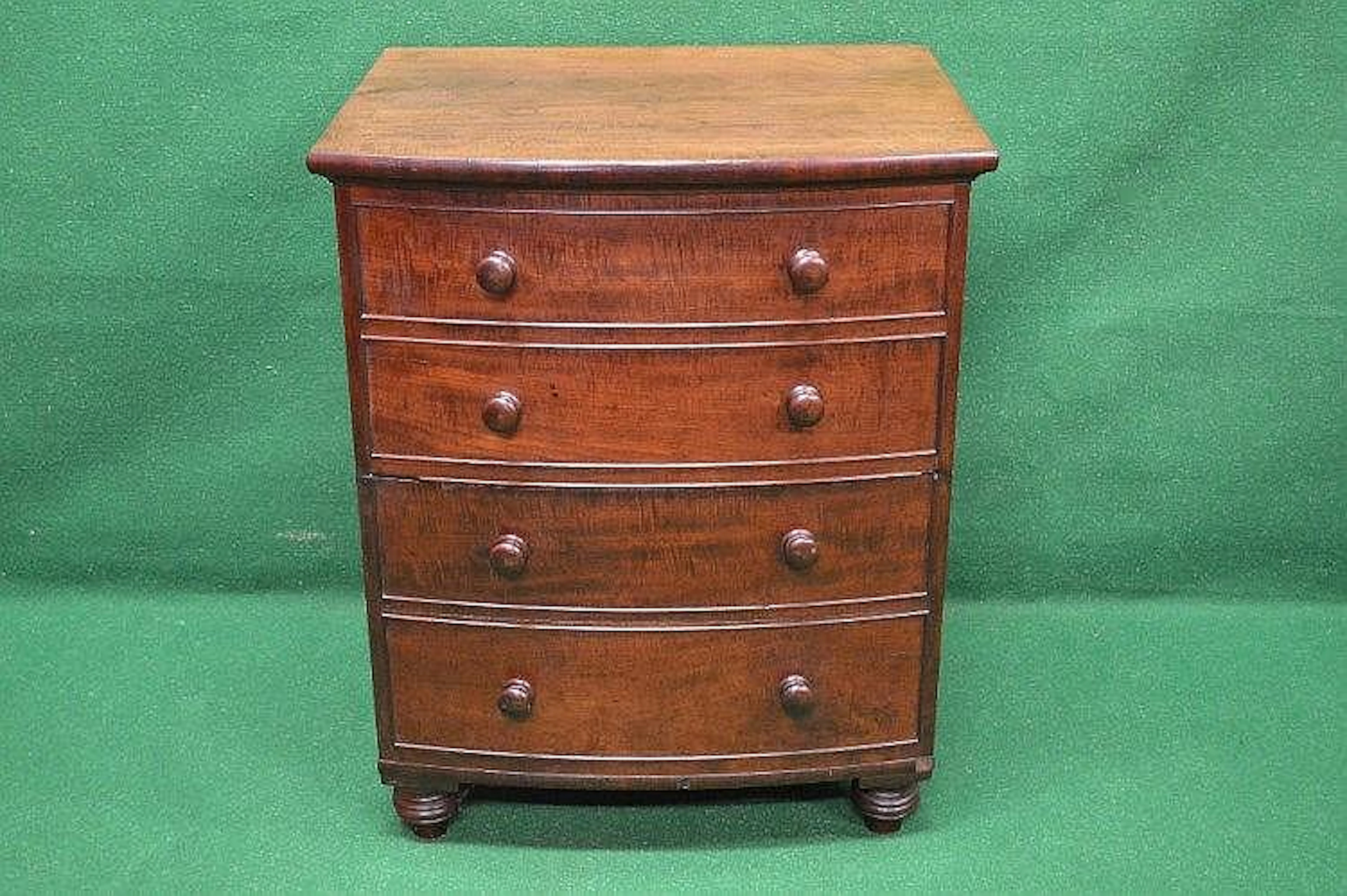 A mahogany bow fronted commode having four simulated drawers with knob handles