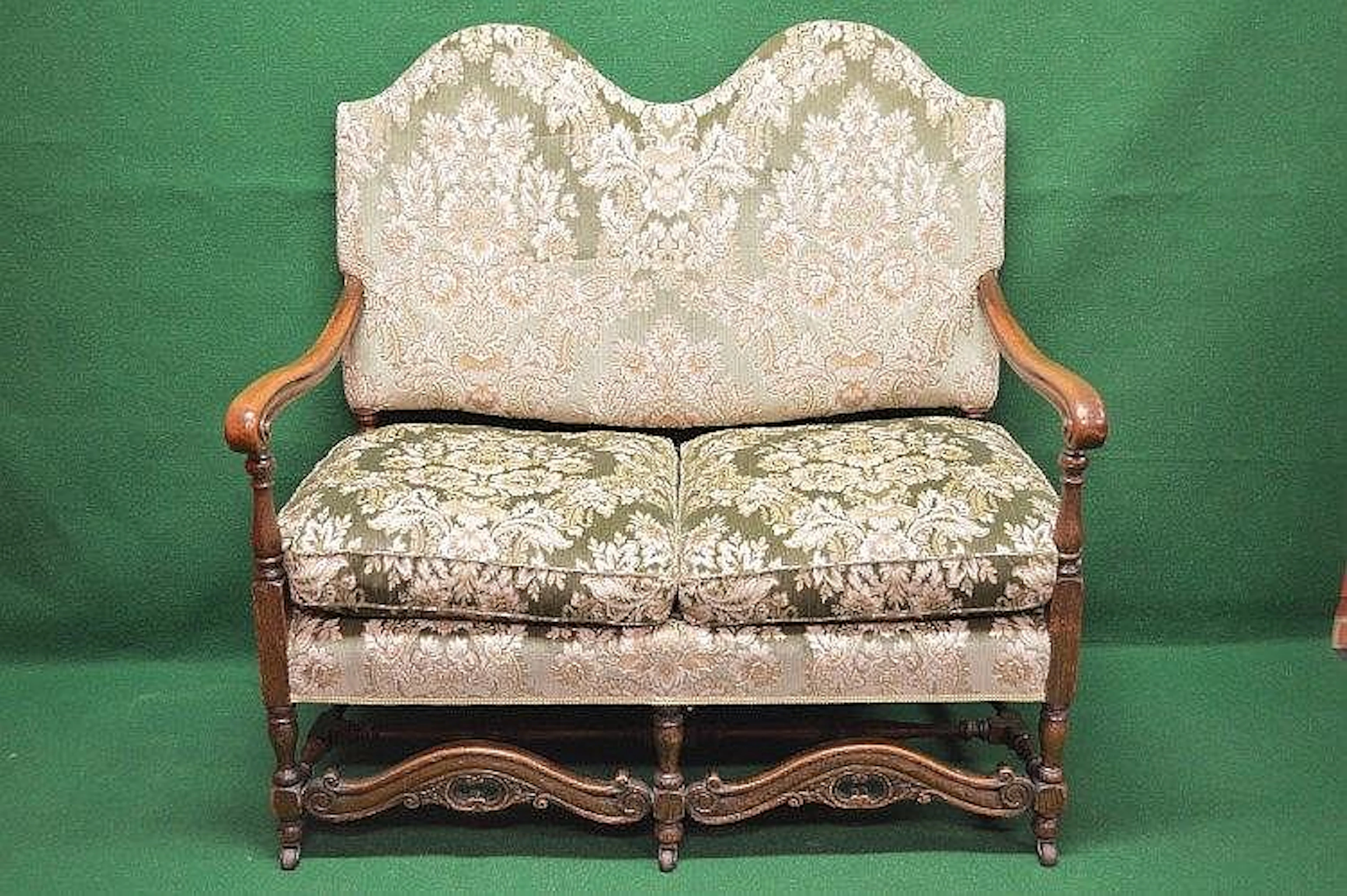 Oak framed two seater settee with green floral upholstery...