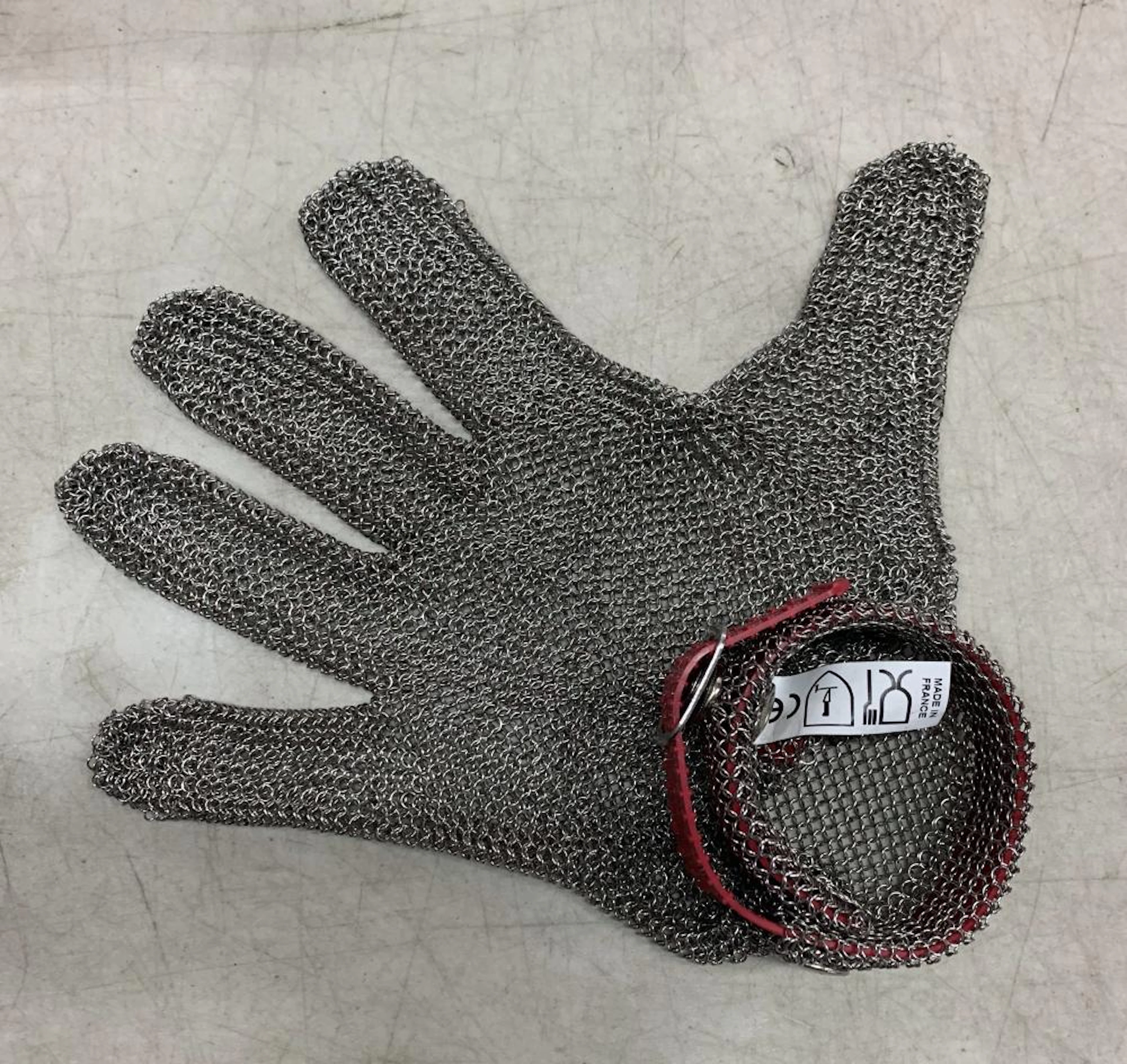 A stainless steel chain mail protective glove marked Honeywell with red band