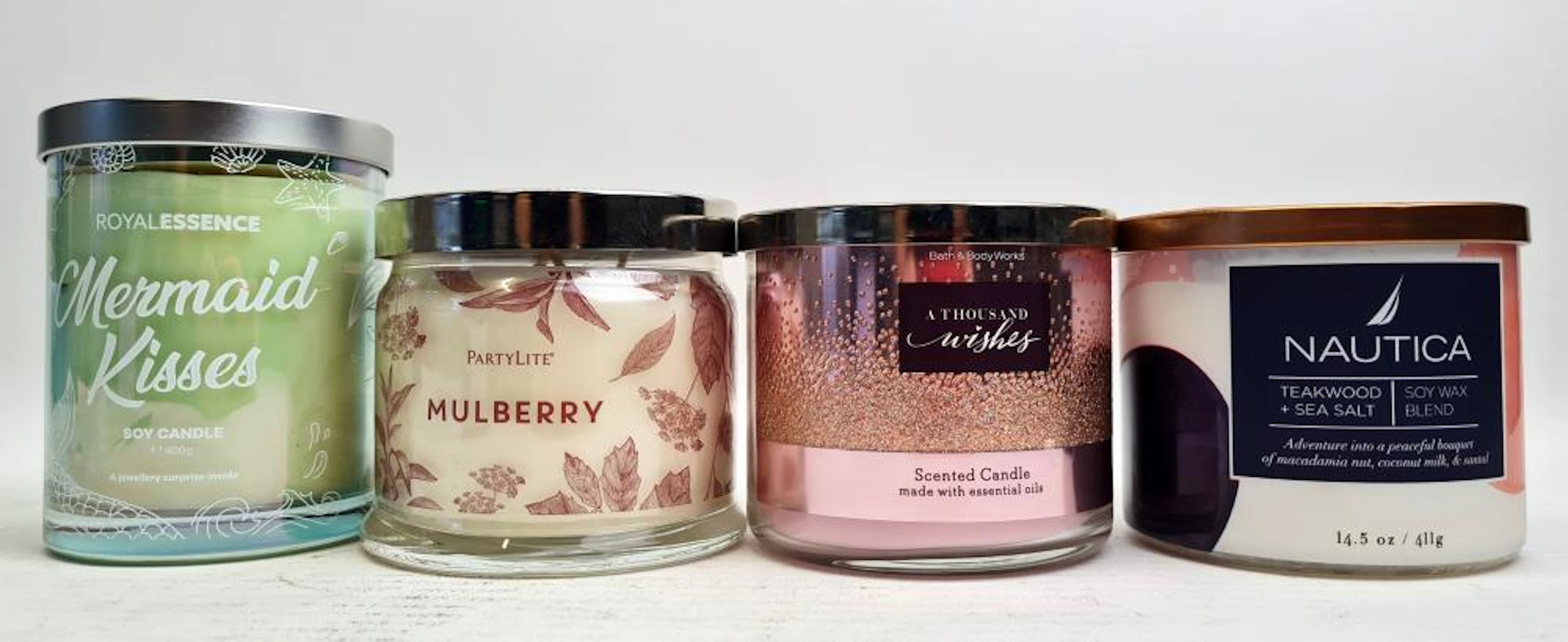Four scented candles marked Nautica, Party Life & Royal Wished etc