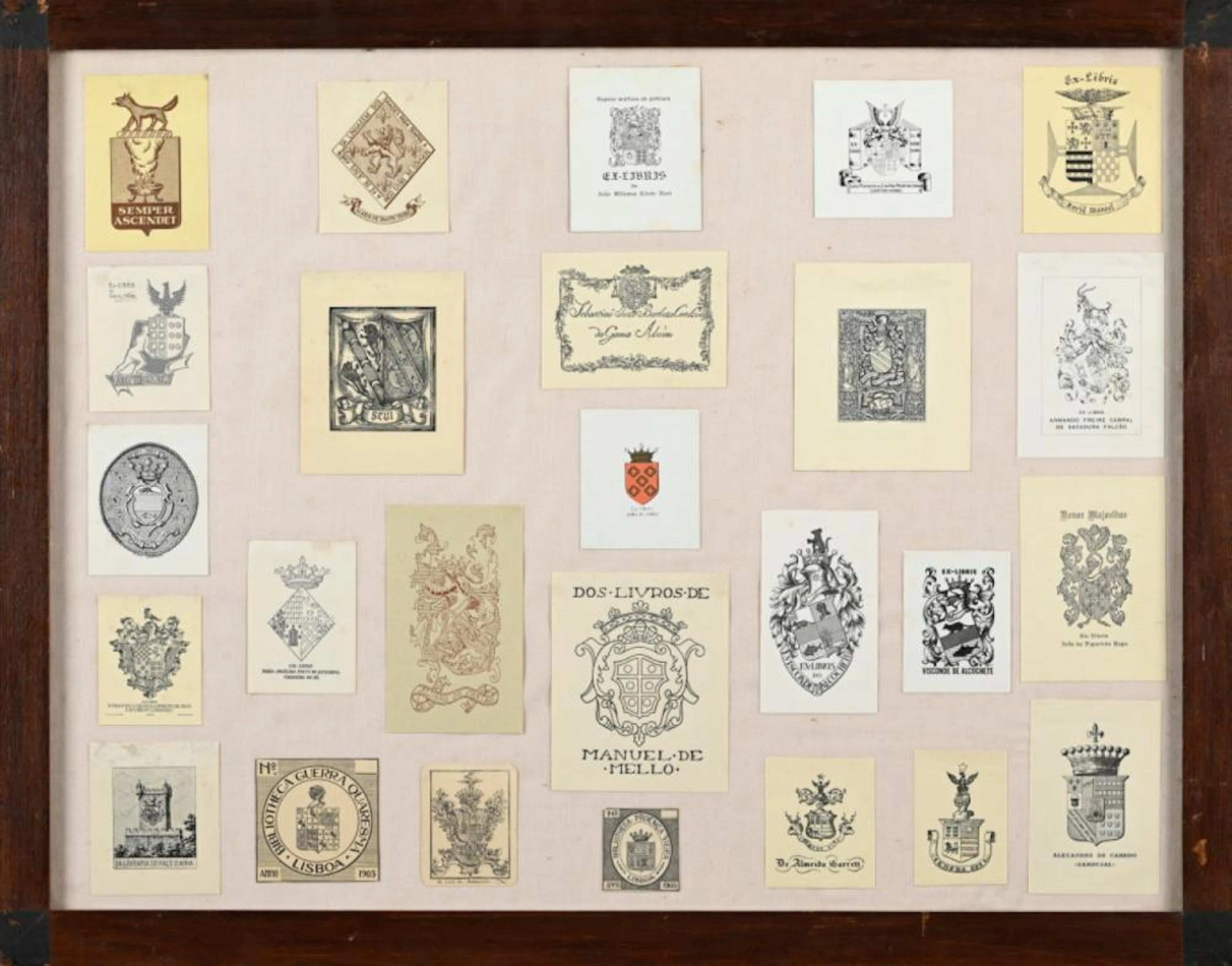Lote de 26 ex-libris dispostos sobre tecido e cartão. Emoldurado