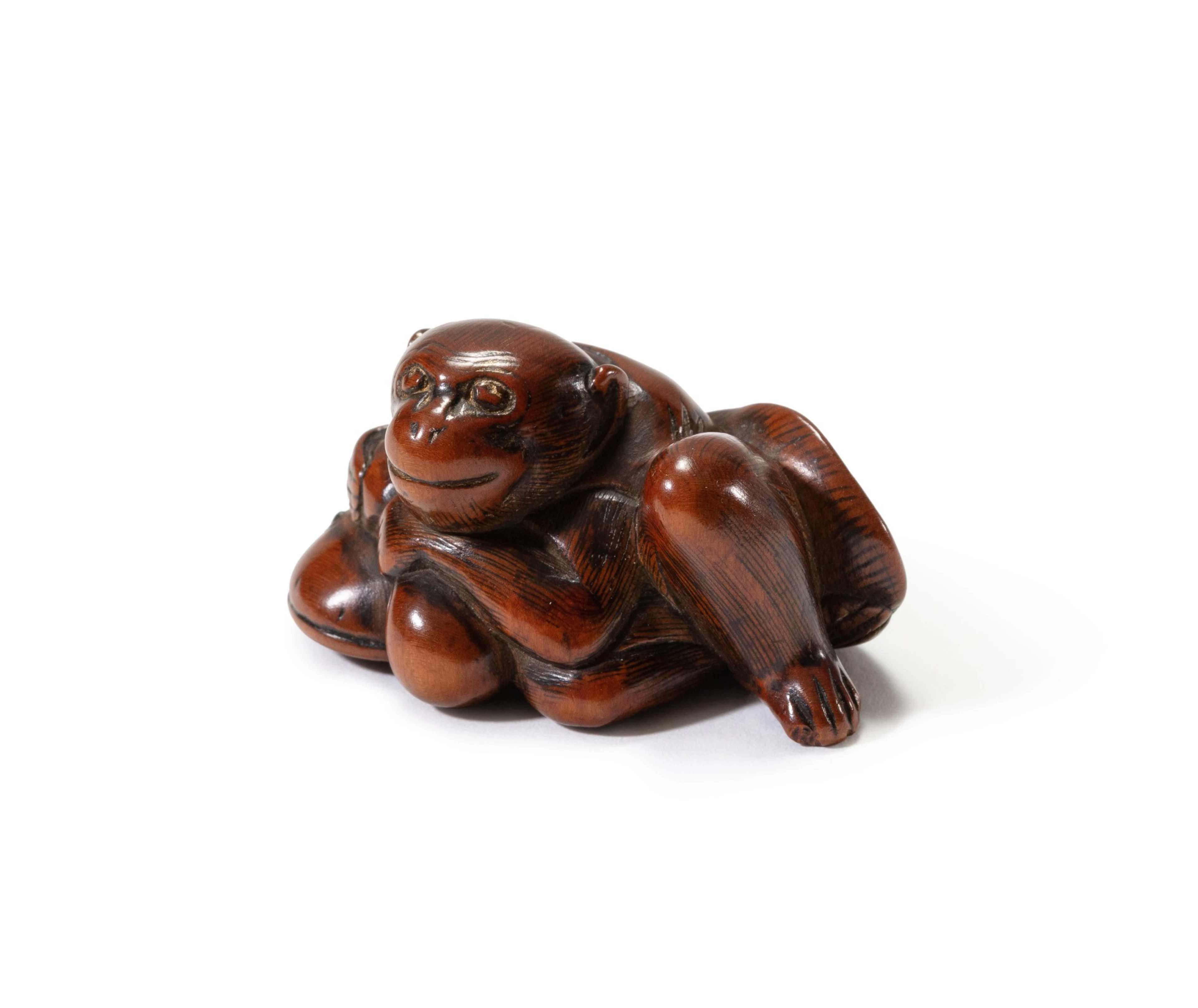 A carved wood study of a monkey clutching the back of a catfish Japan