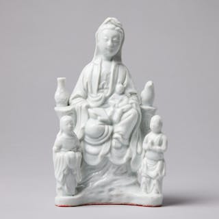 A BLANC-DE-CHINE FIGURE OF GUANYIN, seated on a rocky base and accompanied