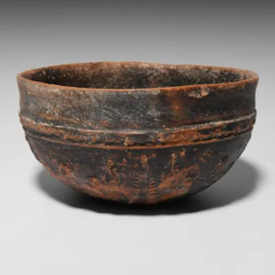 A hemispherical black-glazed terracotta bowl with everted rim, raised ...