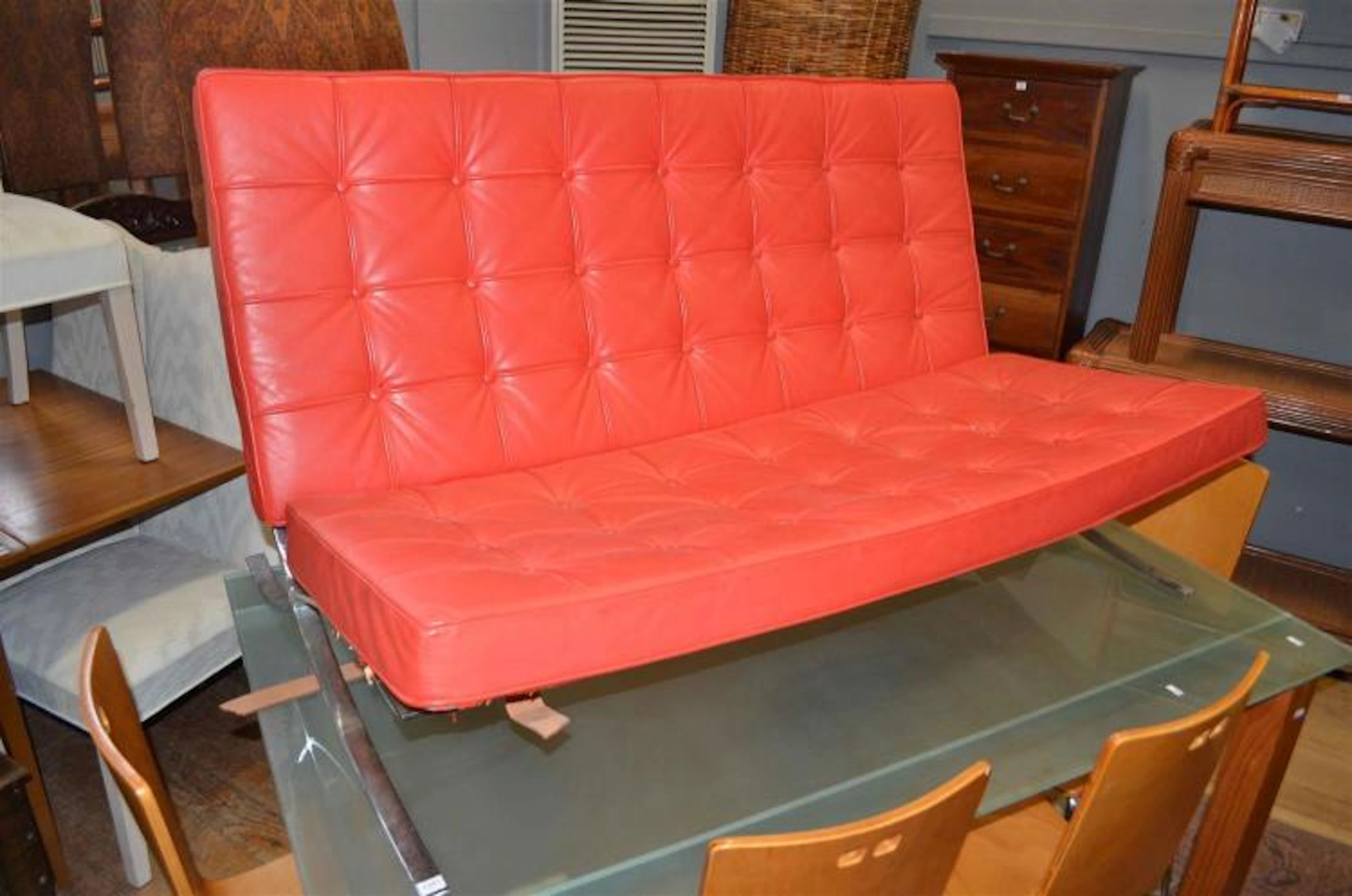 A BARCELONA STYLE TWO SEAT SOFA IN RED VINYL (FAULTS TO UNDERSIDE)