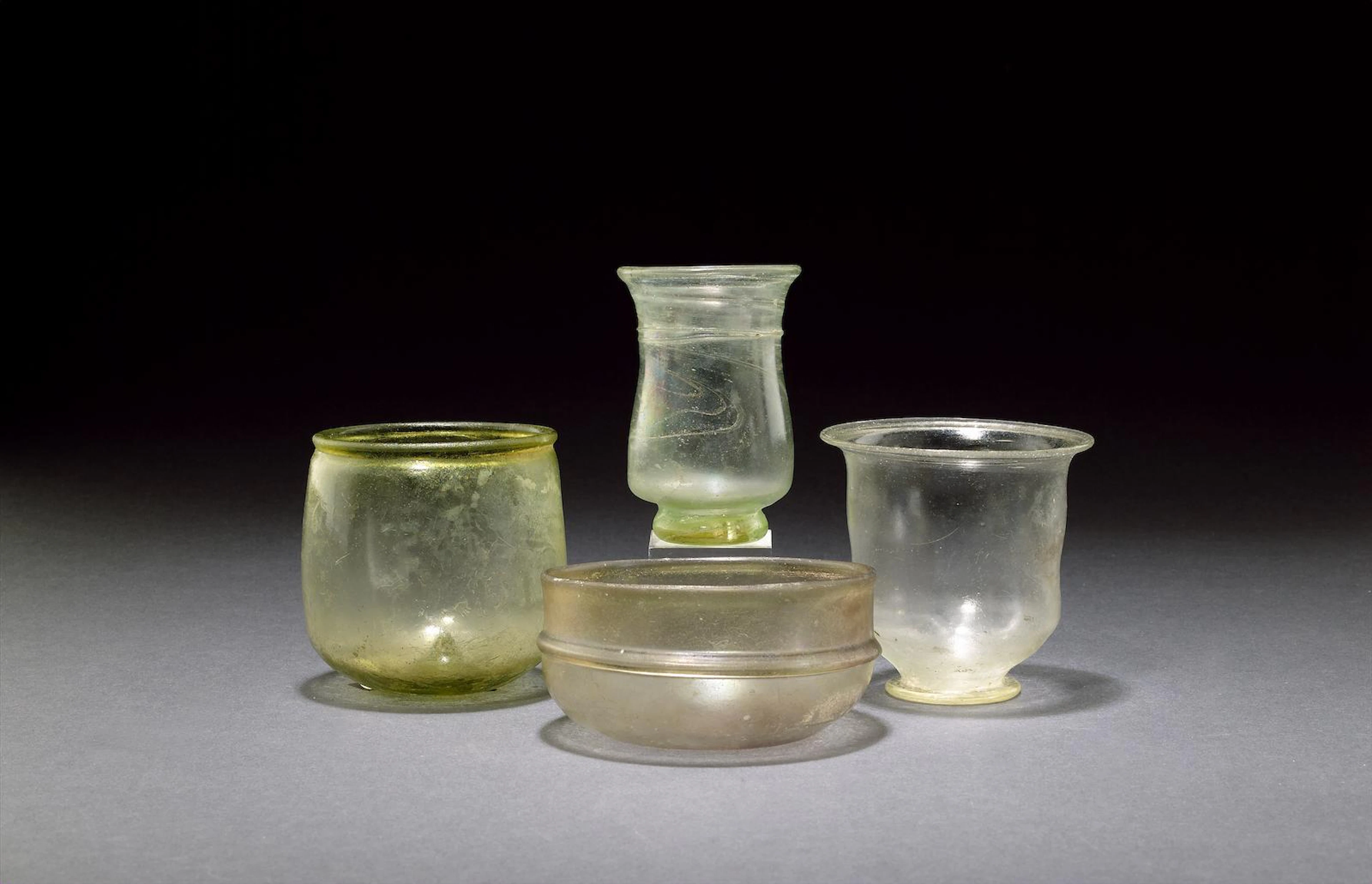 A Roman pale purple glass bowl a Roman pale green glass beaker, a Roman colourless glass beaker, and a Roman pale olive green glass beaker, 4