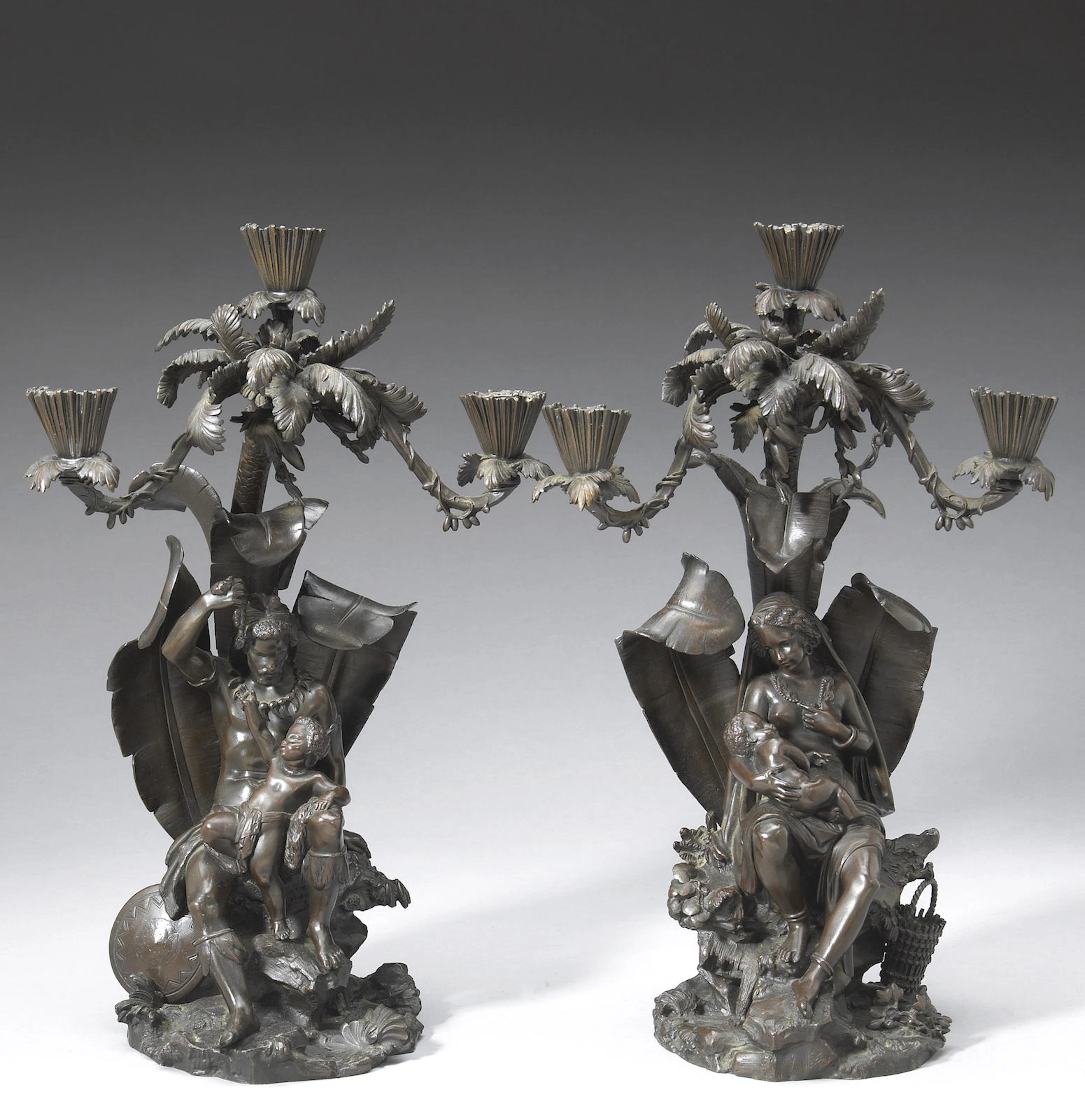 A pair of English patinated bronze three light figural candelabra allegorical of the New World