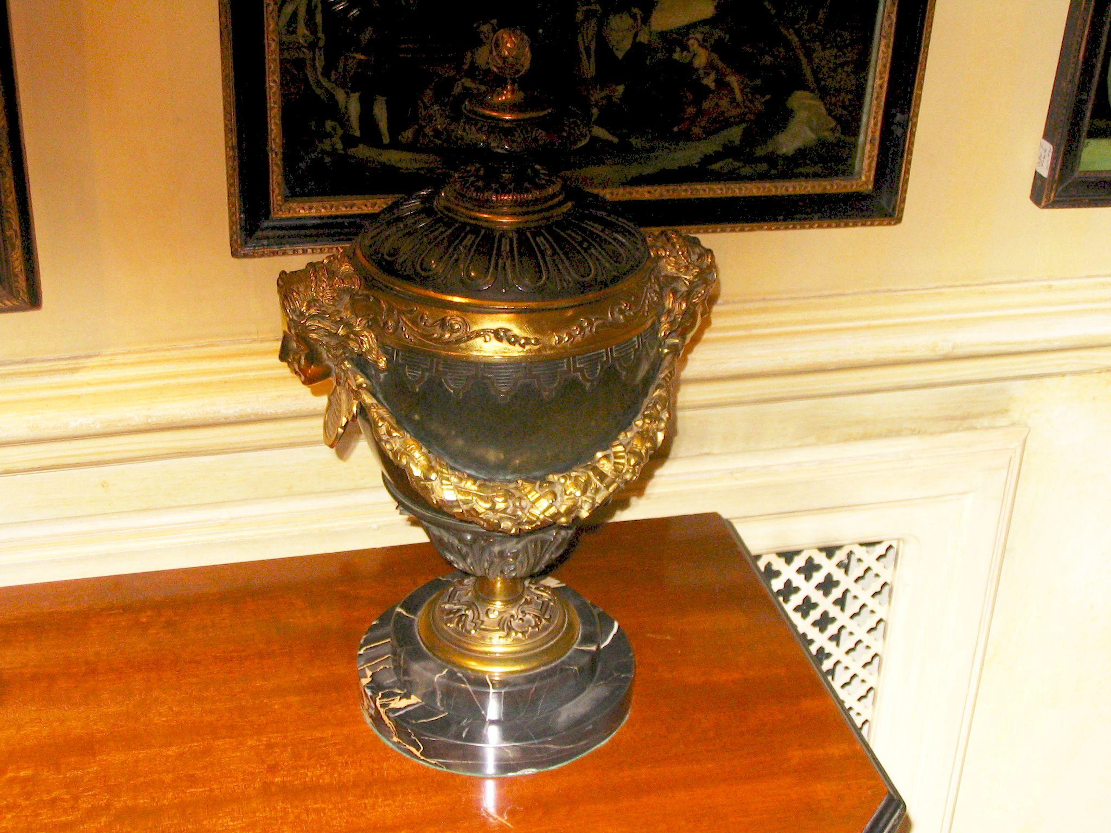 A pair of late 19th / early 20th century patinated and gilt bronze urns and covers