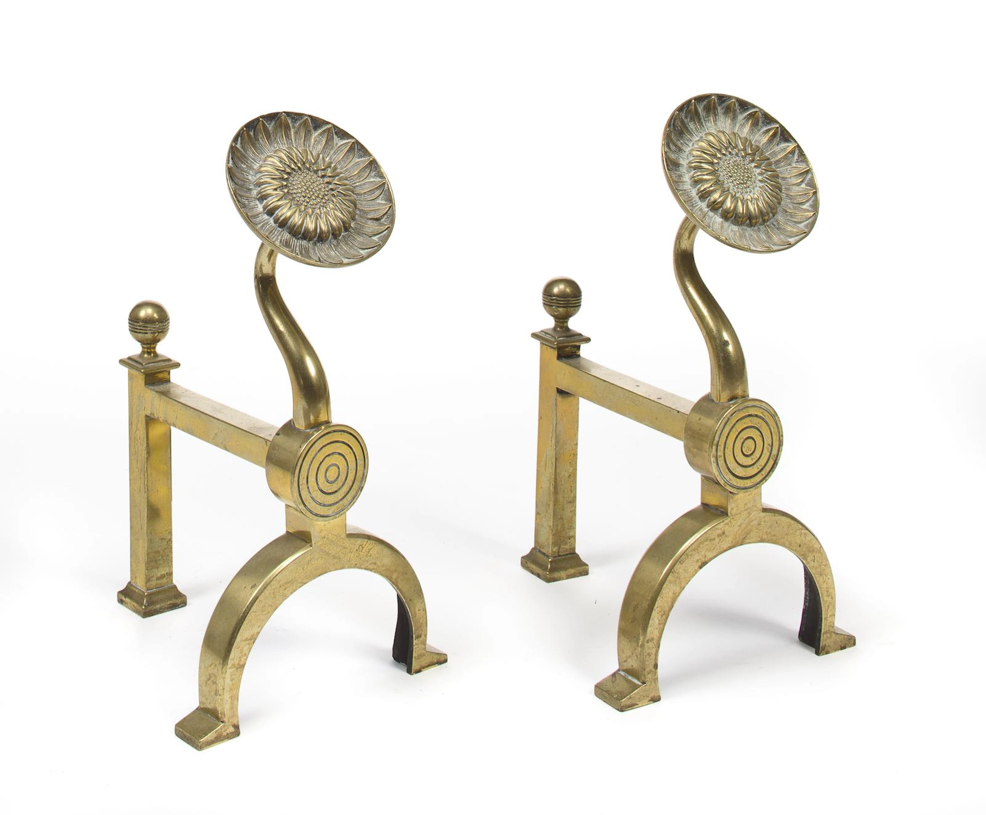 A pair of English Aesthetic Movement brass sunflower andironsmanufactured by Benham and Froud, Londonfourth quarter 19th century