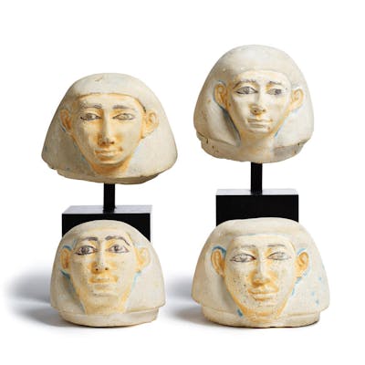 Four Egyptian limestone human-headed canopic jar lids