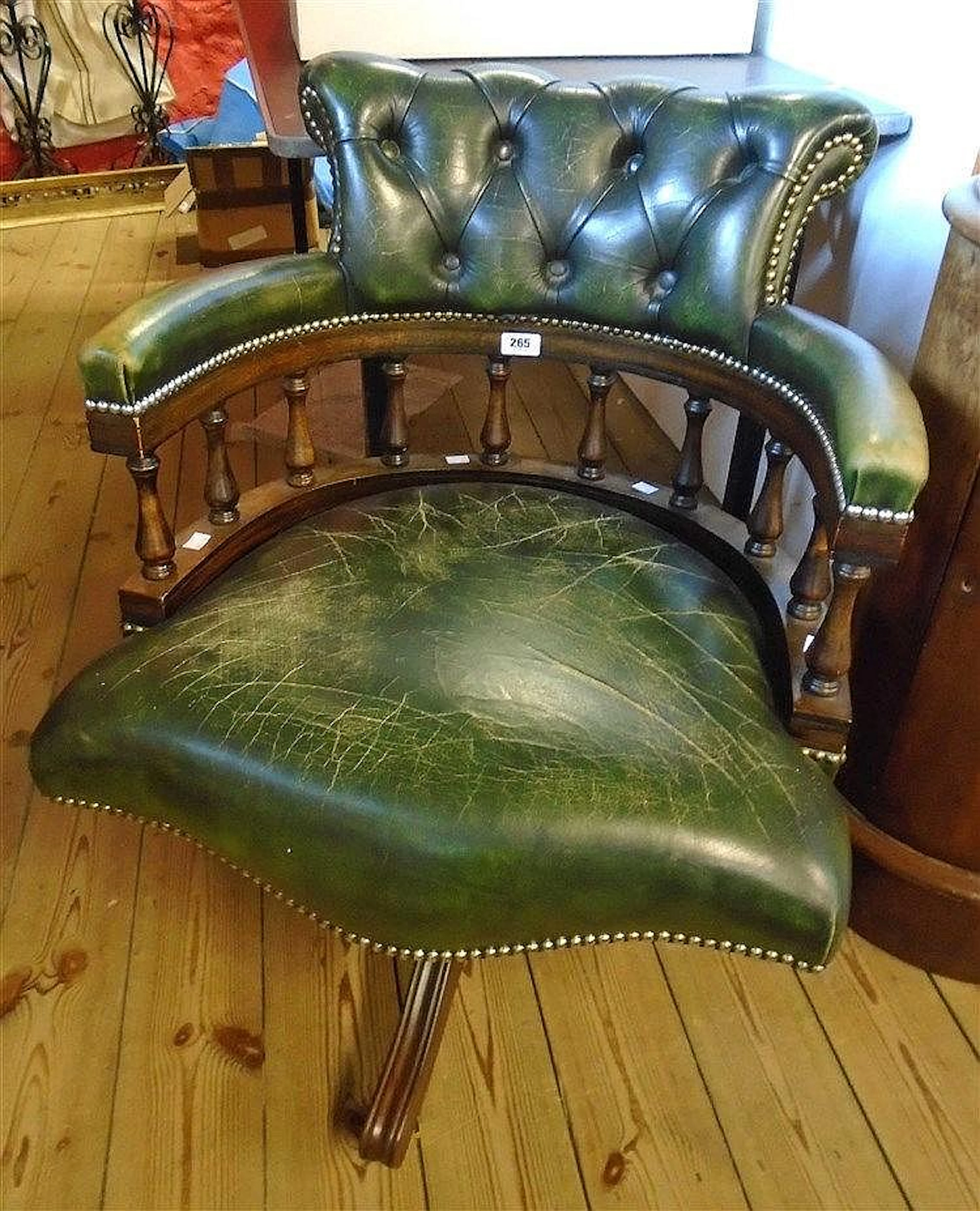A stained wood framed green leather button back captain's style swivel elbo