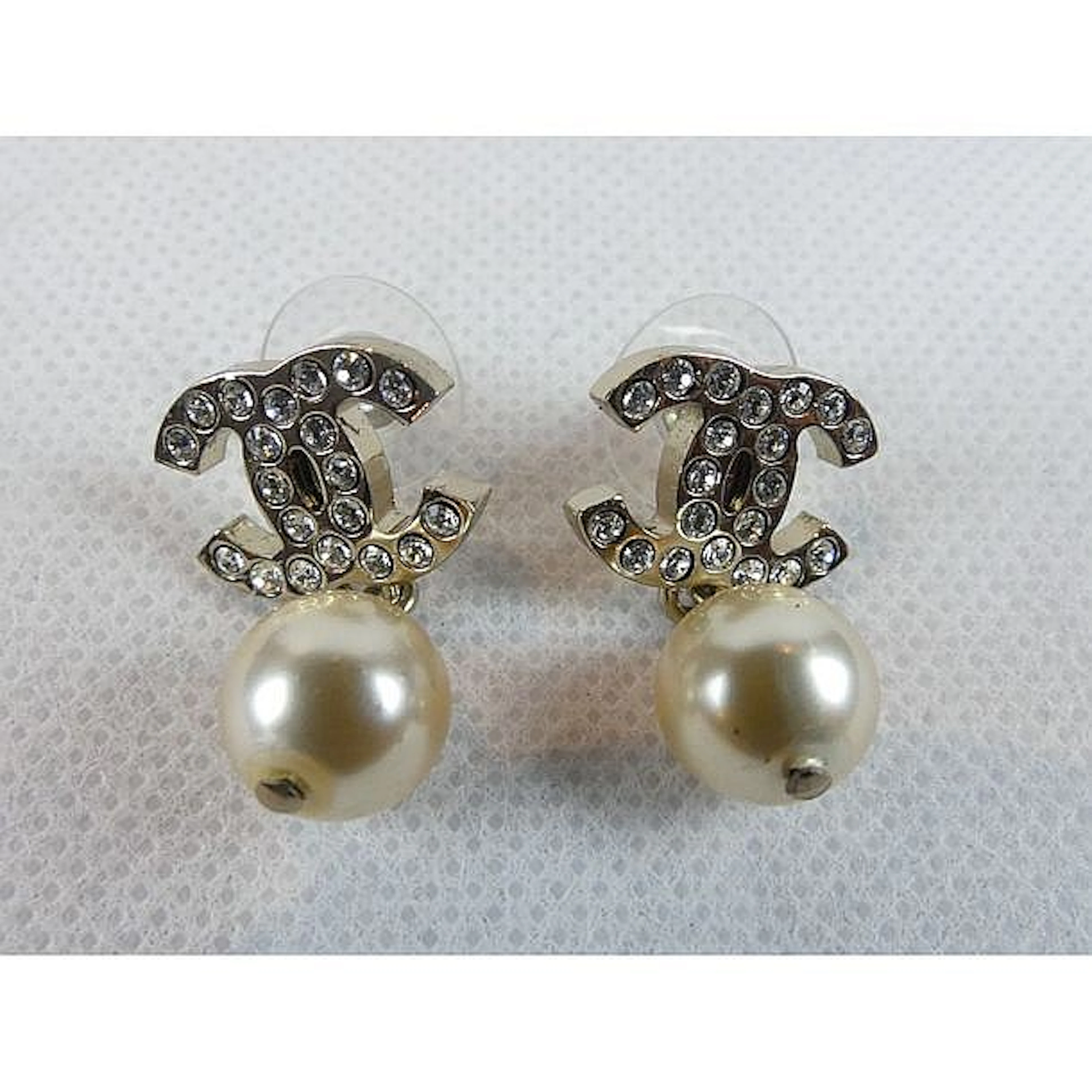 CHANEL. Paire de boucles d?oreilles en métal argenté ornées du sigle serti