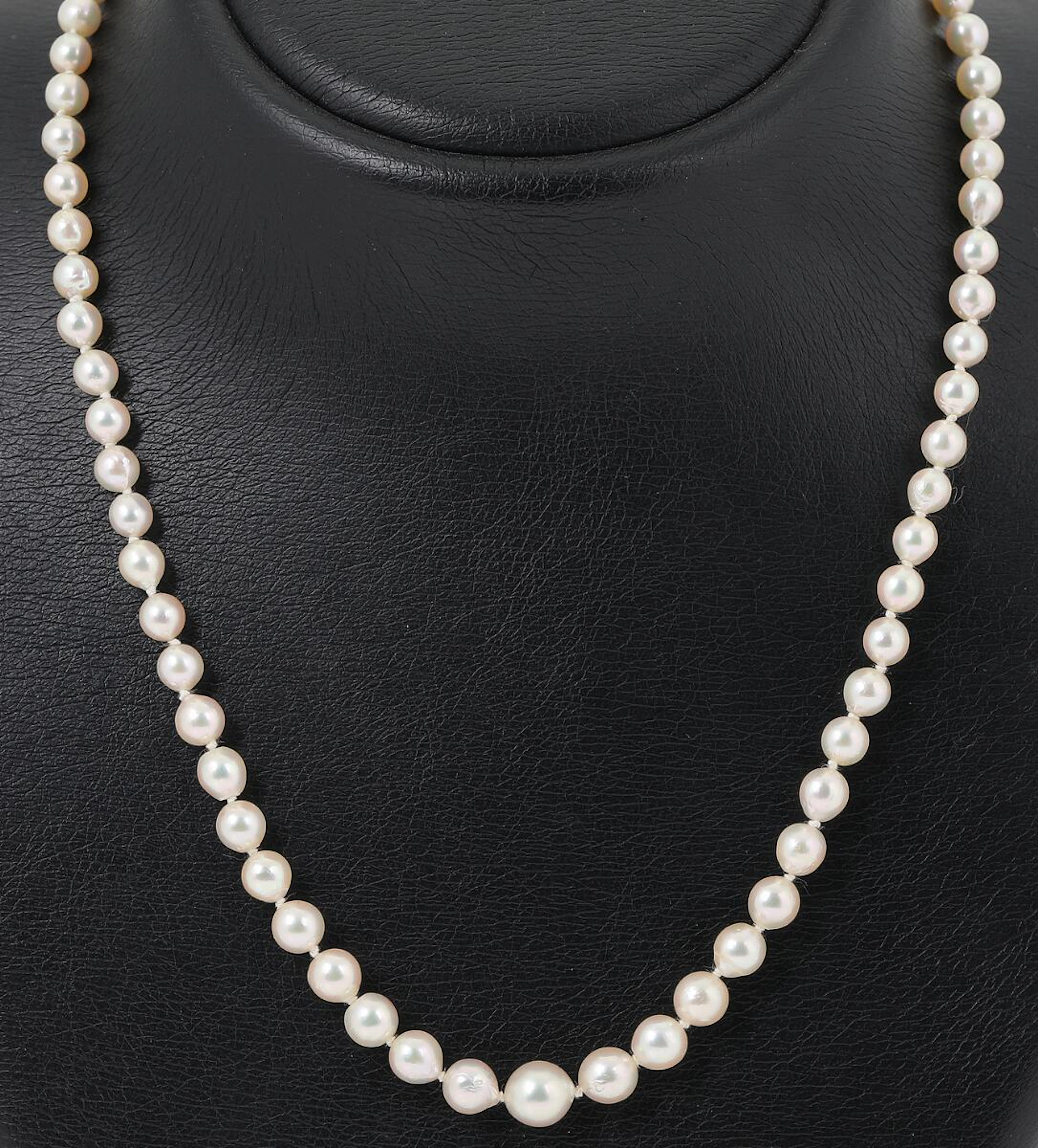 A pearl necklace set with numerous cultured pearls and a pearl and zircon clasp