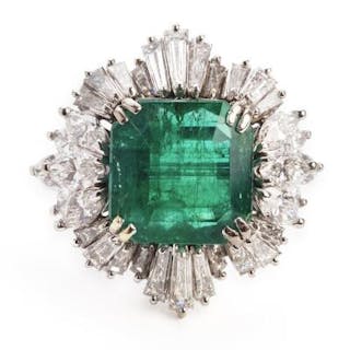 An emerald and diamond ring set with an emerald encircled by numerous
