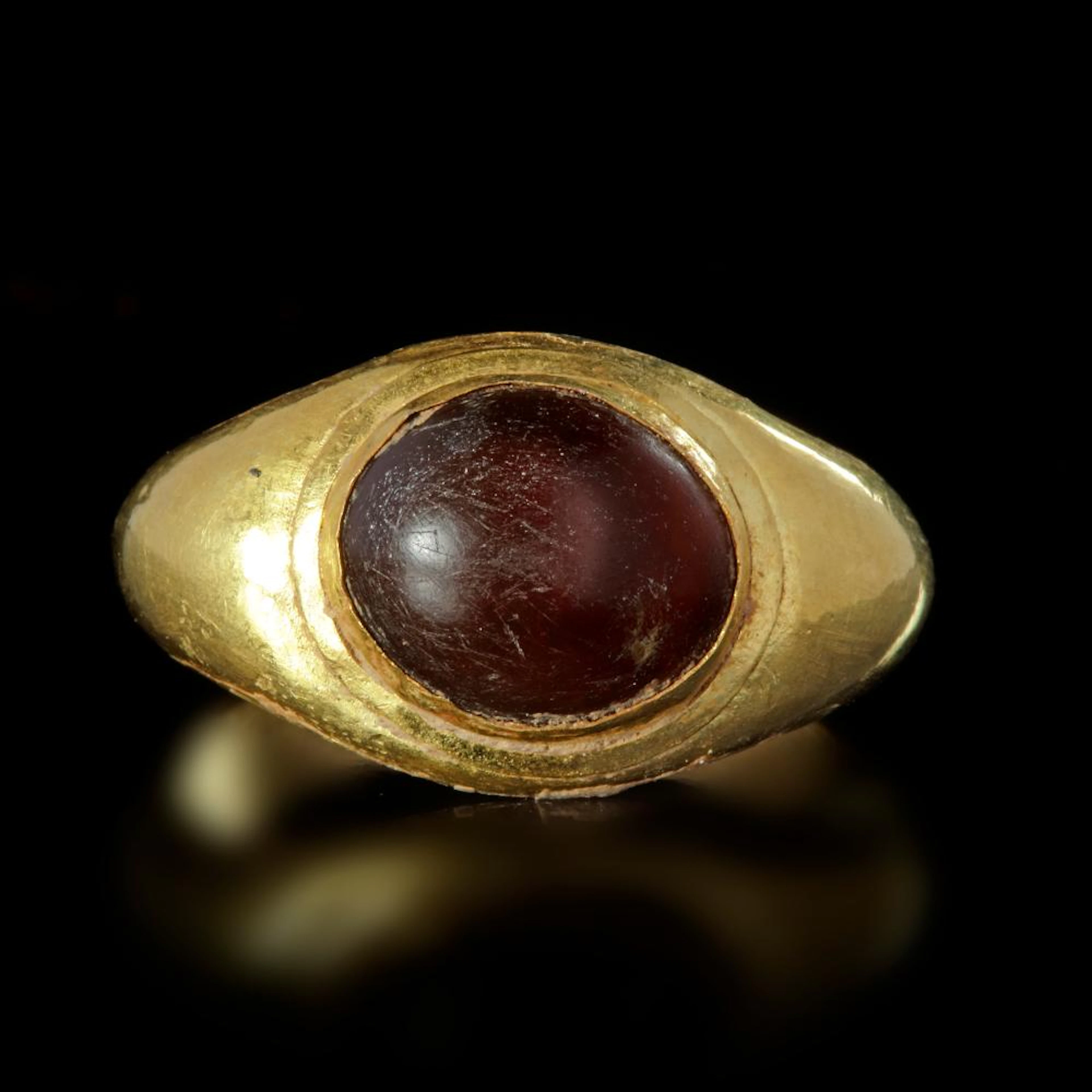 A HOLLOW ROMAN GOLD RING WITH A CABOCHON DARK BROWN CARNELIAN INSET