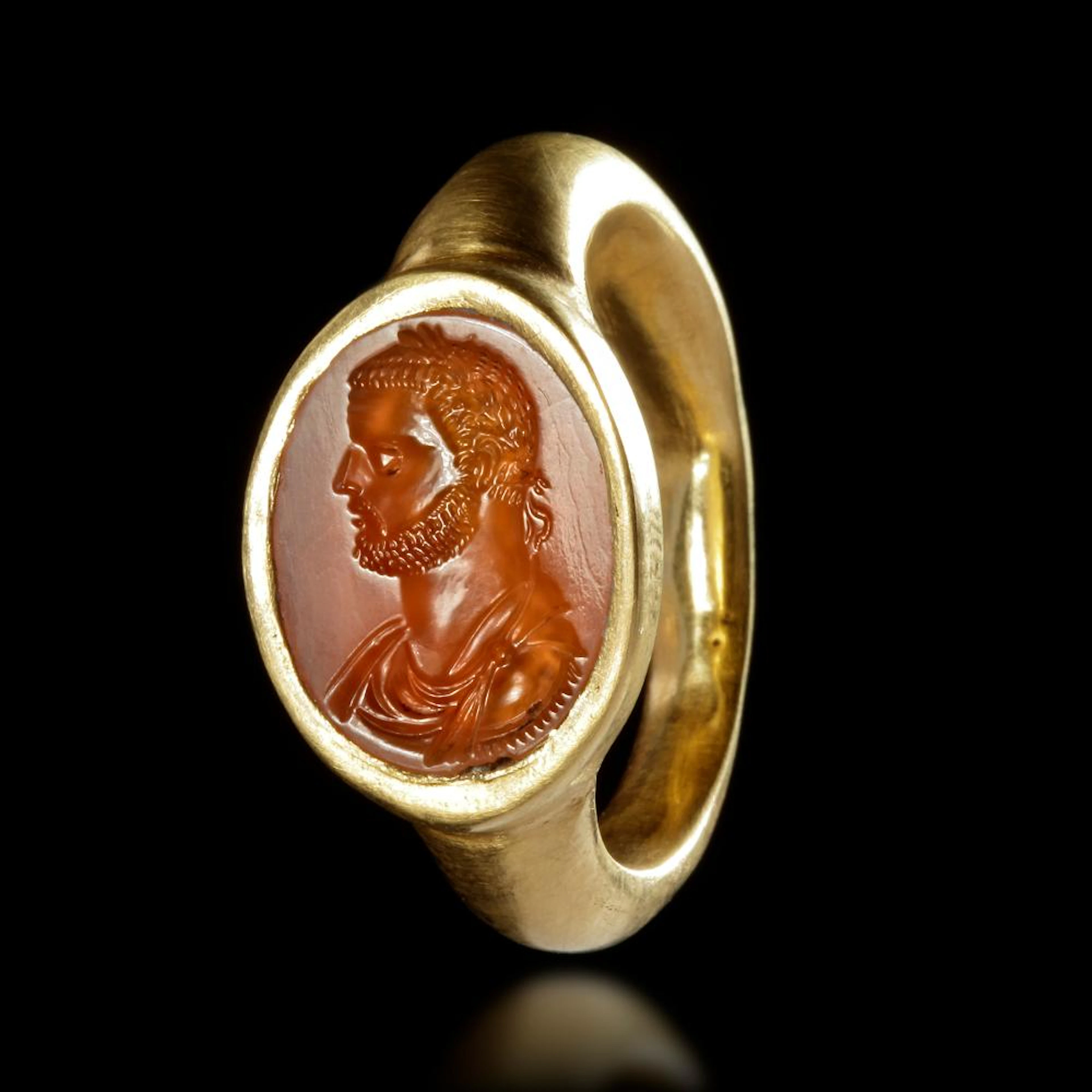 A ROMAN GOLD RING WITH A CARNELIAN INTAGLIO SHOWING THE HEAD OF AN EMPEROR