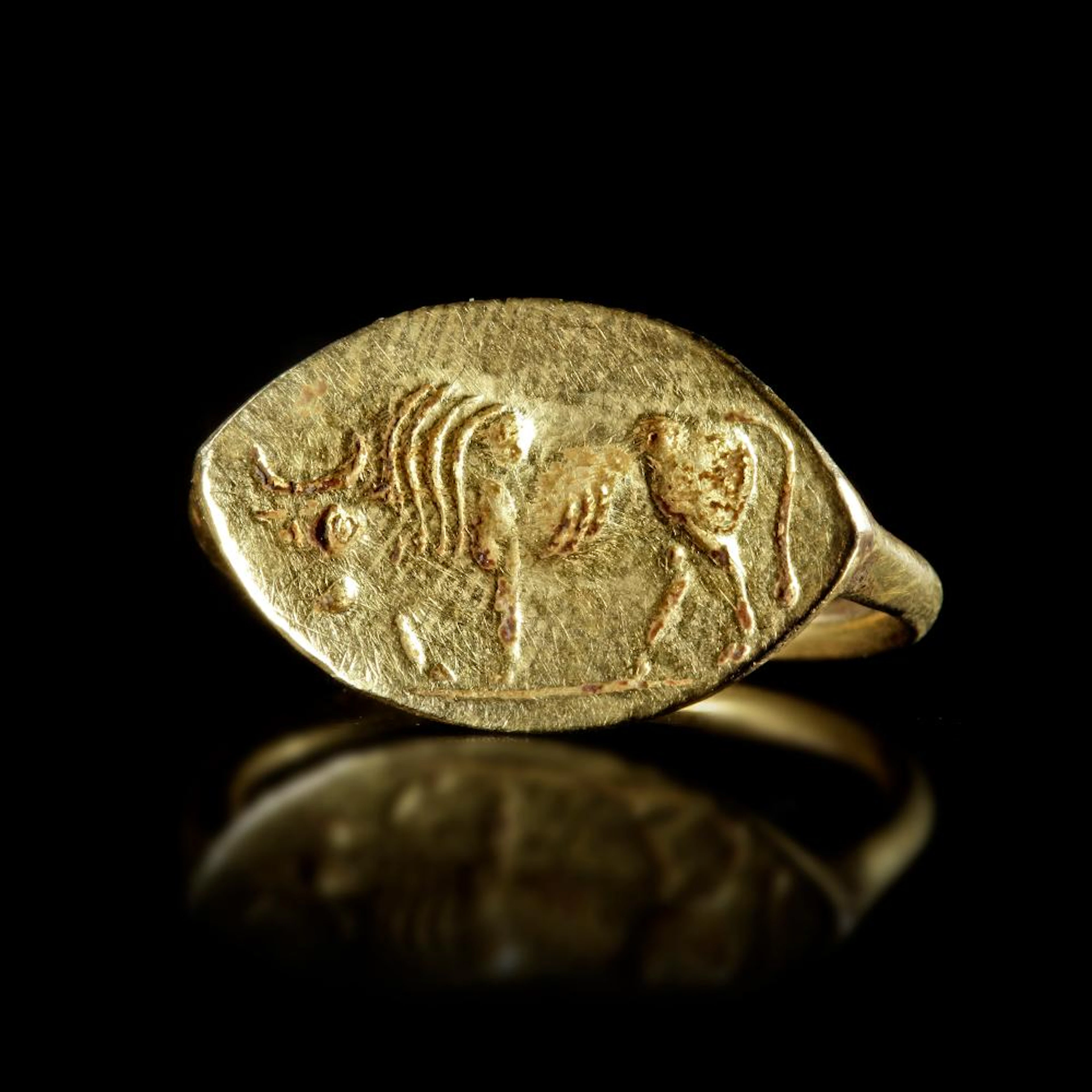AN ARCHAIC GREEK GOLD RING WITH A BULL, CIRCA LATE 6TH CENTURY BC