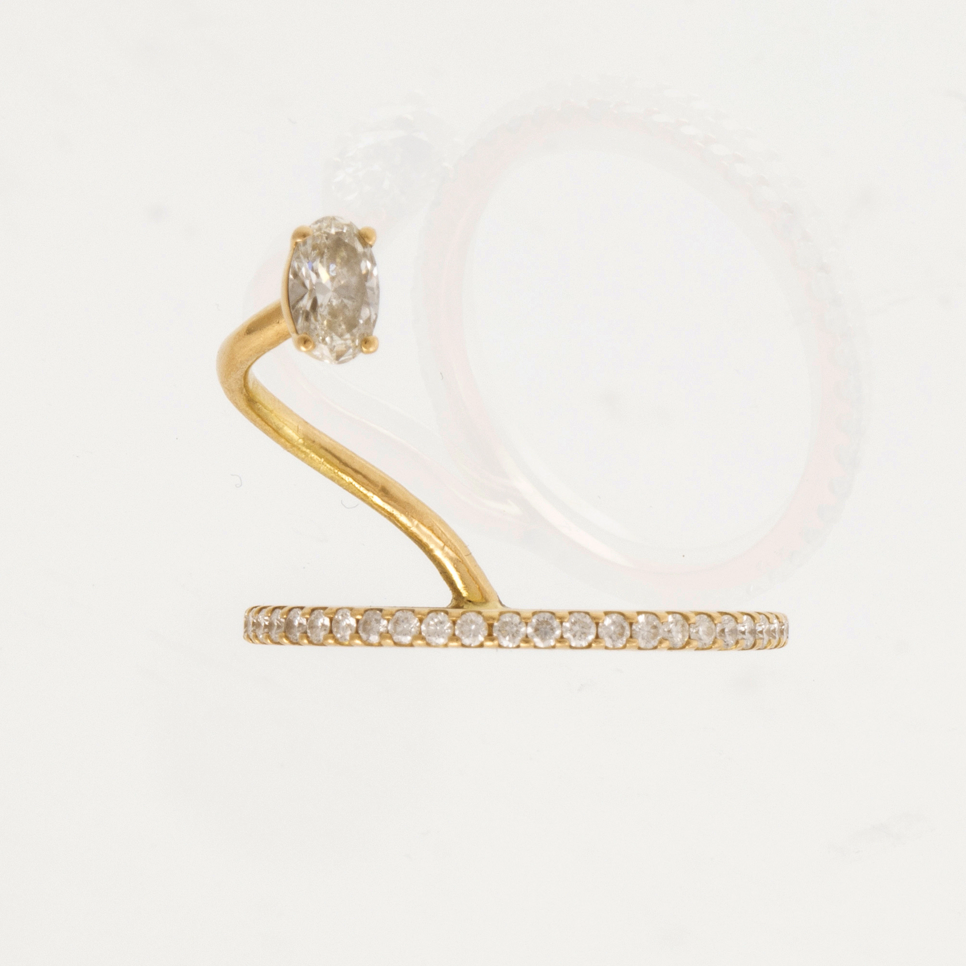 An 18K gold ring set with an oval cut and round brilliant...