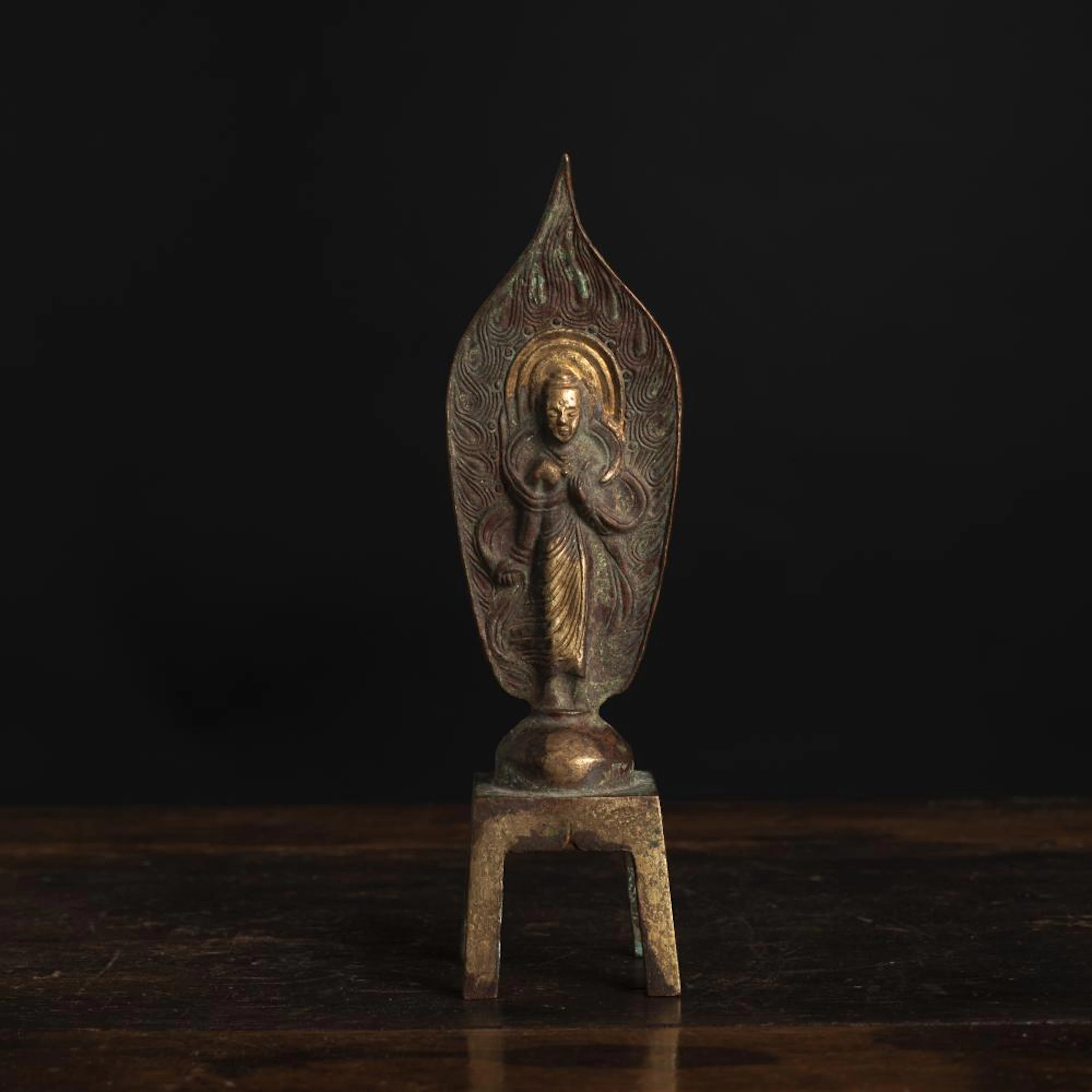 A PARCEL-GILT BRONZE FIGURE OF GUANYIN STANDING ON A FOUR-LEGGED PEDESTAL
