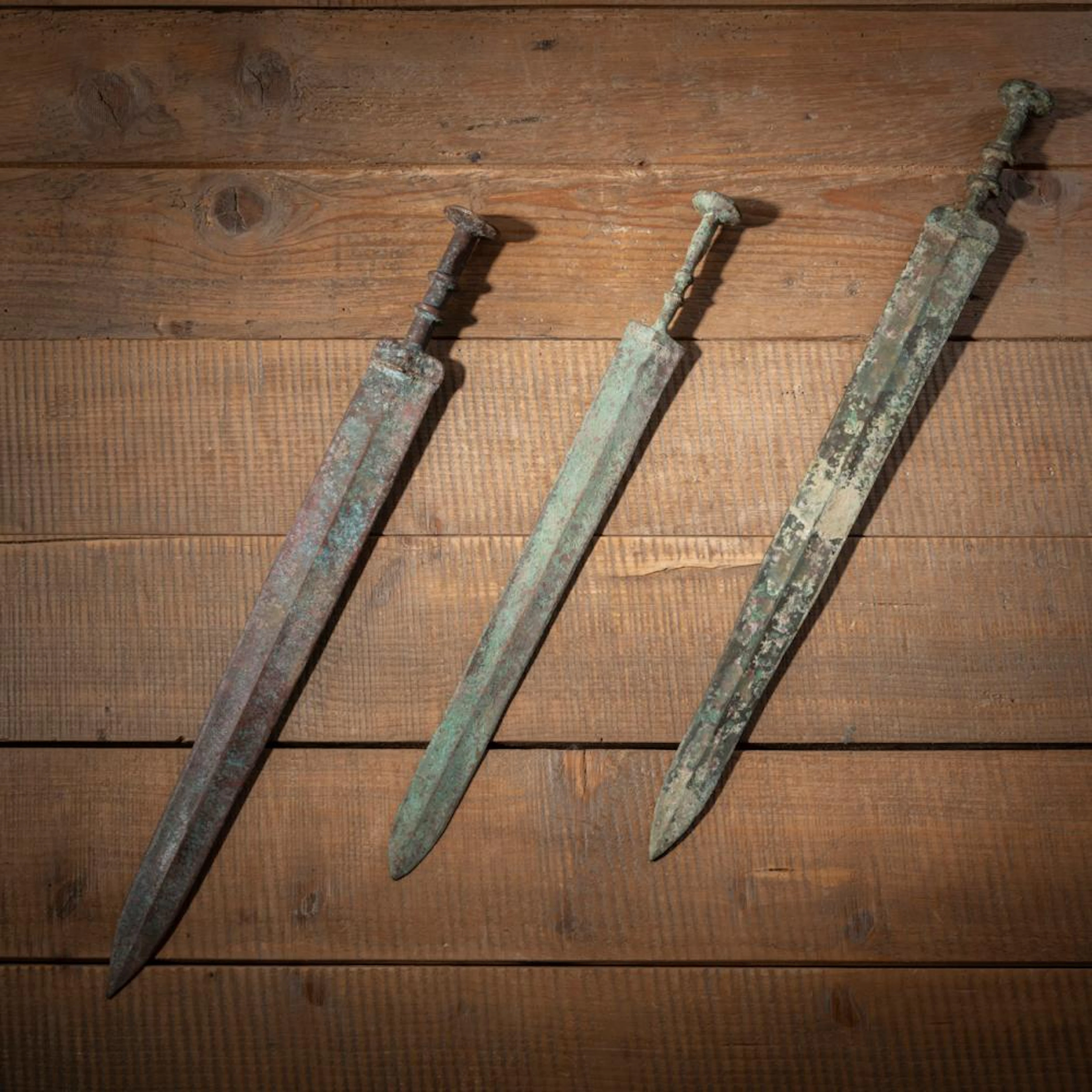 THREE BRONZE SWORDS WITH GREEN AND BROWN PATINA