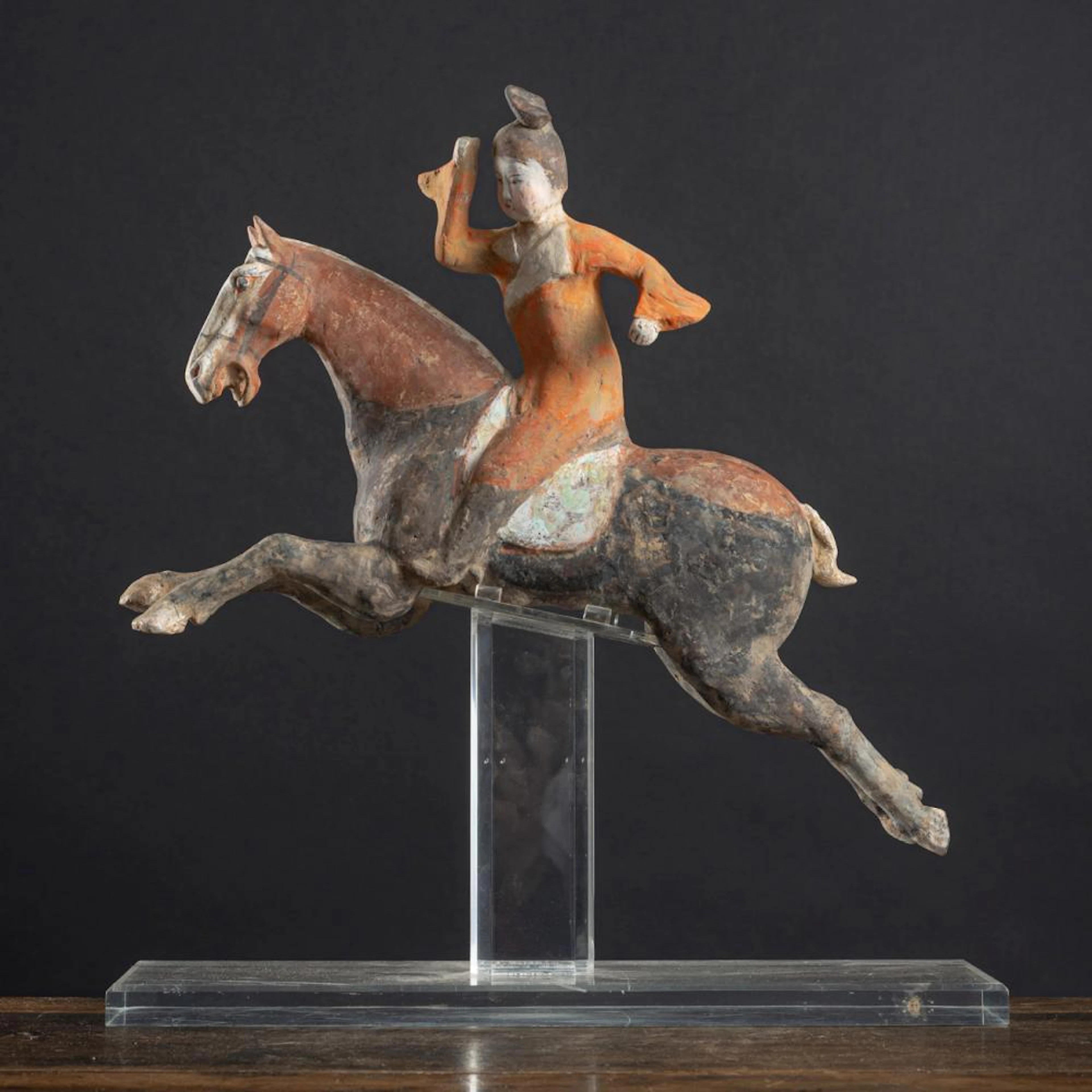 A POLYCHROME PAINTED POTTERY MODEL OF A FEMALE POLO PLAYER ON A HORSE