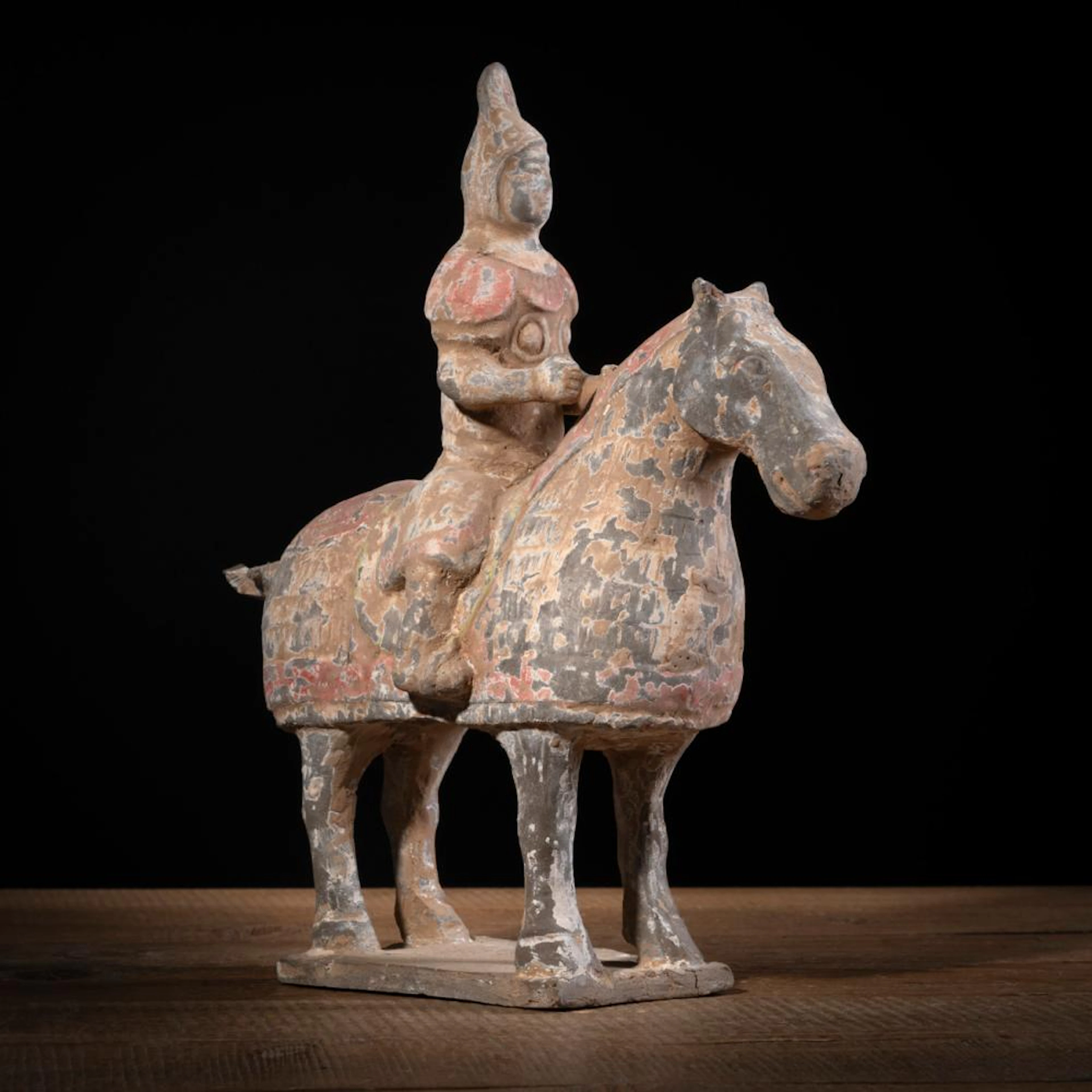 A POTTERY FIGURE OF A MOUNTED HORSE WITH RESIDUE OF PAINTING
