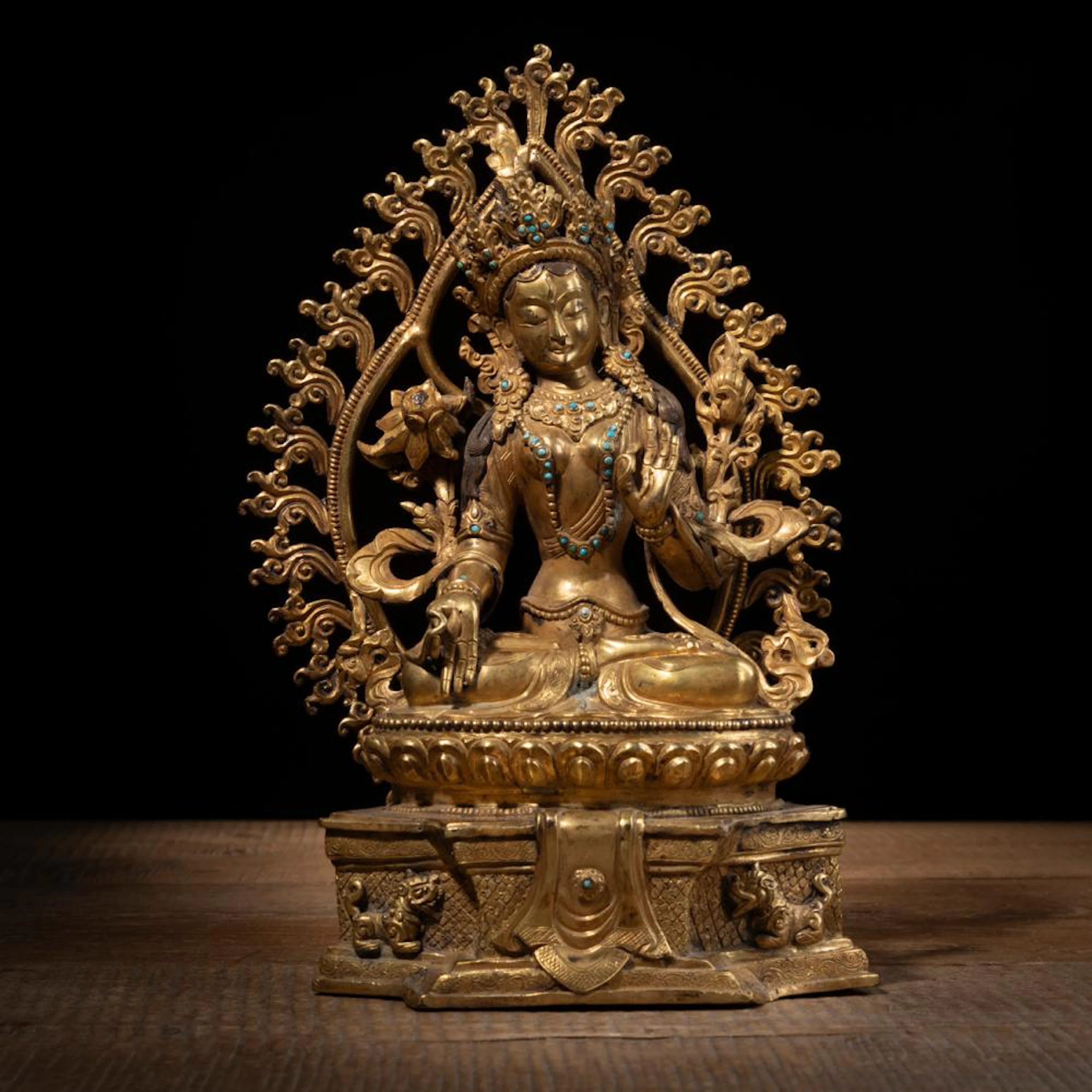 A GILT-BRONZE FIGURE OF SITATARA ON A LOTUS BASE