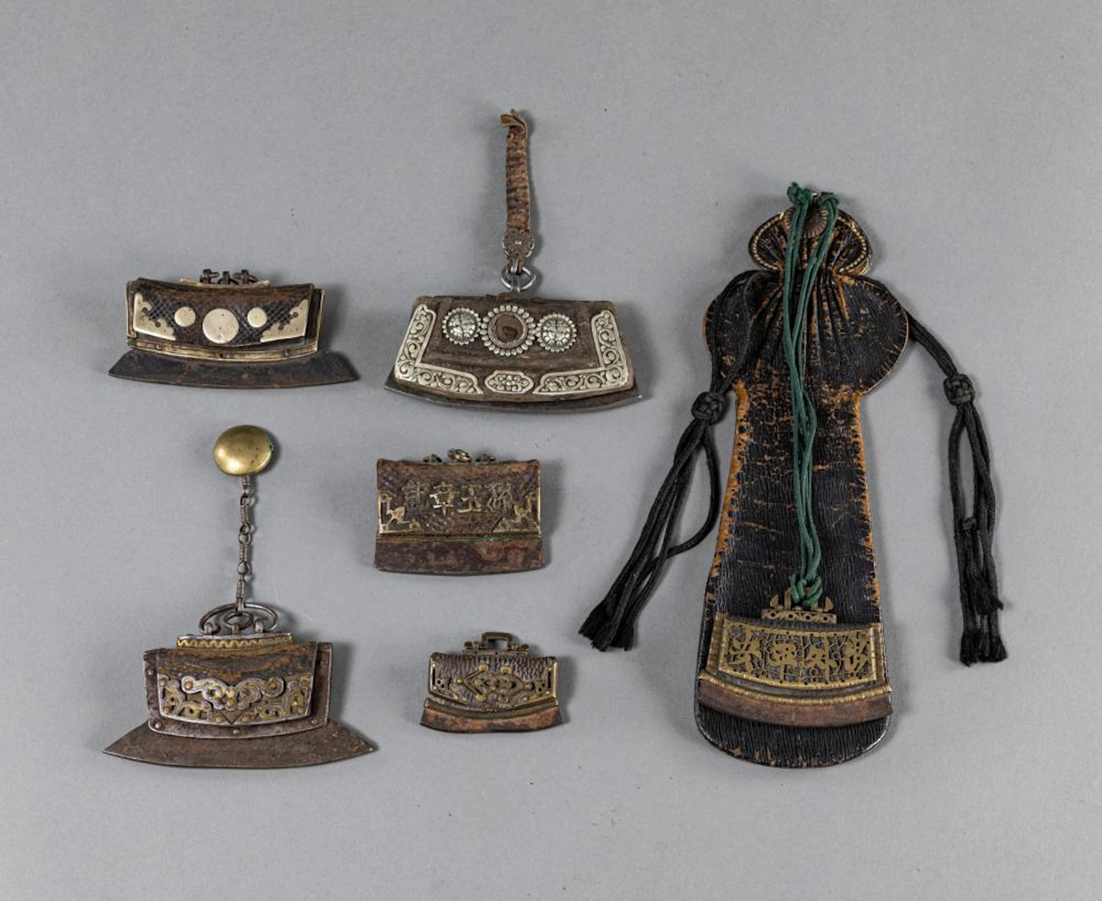A GROUP OF SIX TINDER POUCHES AND ONE LEATHER POUCH WITH RESIDUE OF FLINT