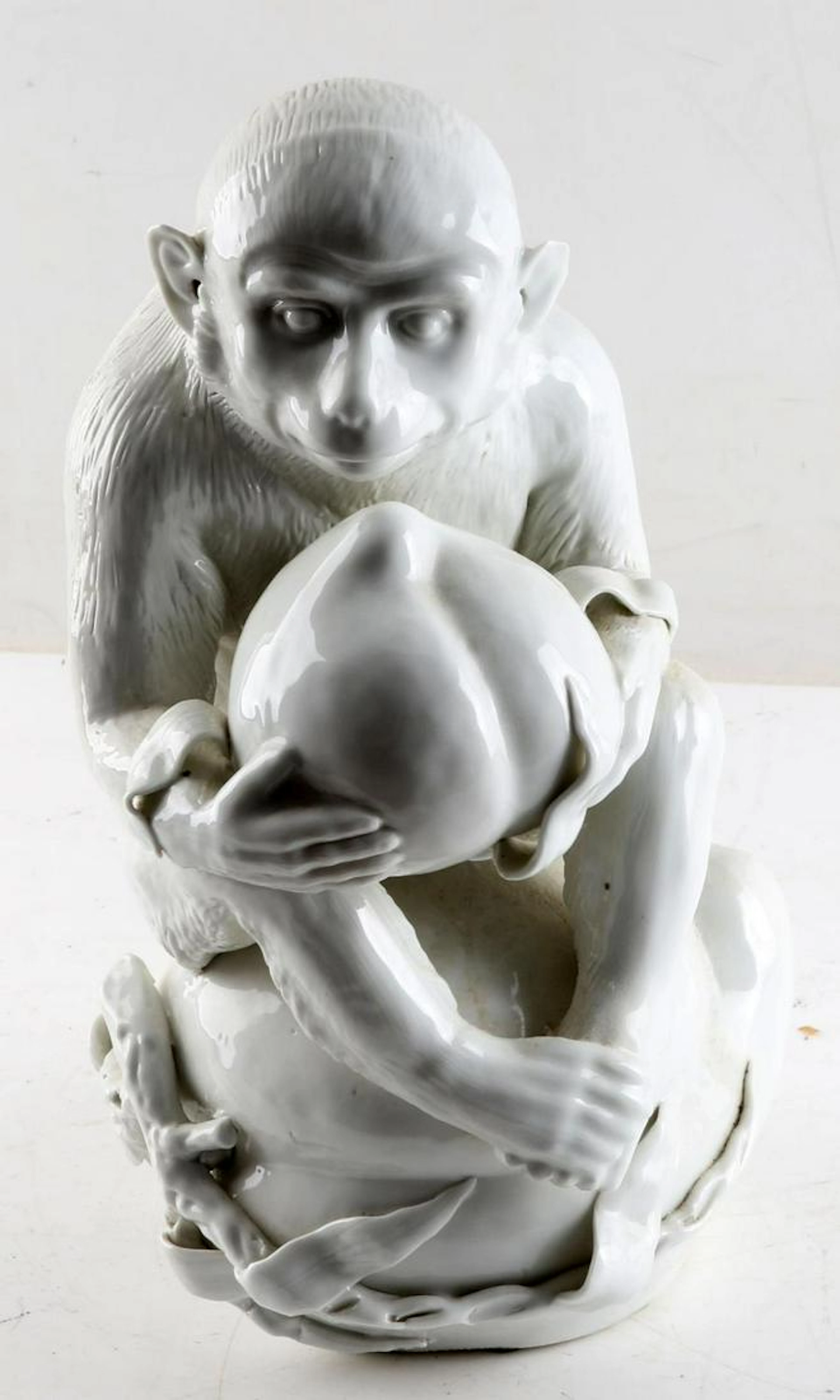 White porcelain monkey holding fruit