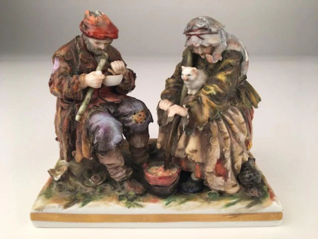 Antique capodimonte figurine of an old couple sitting.