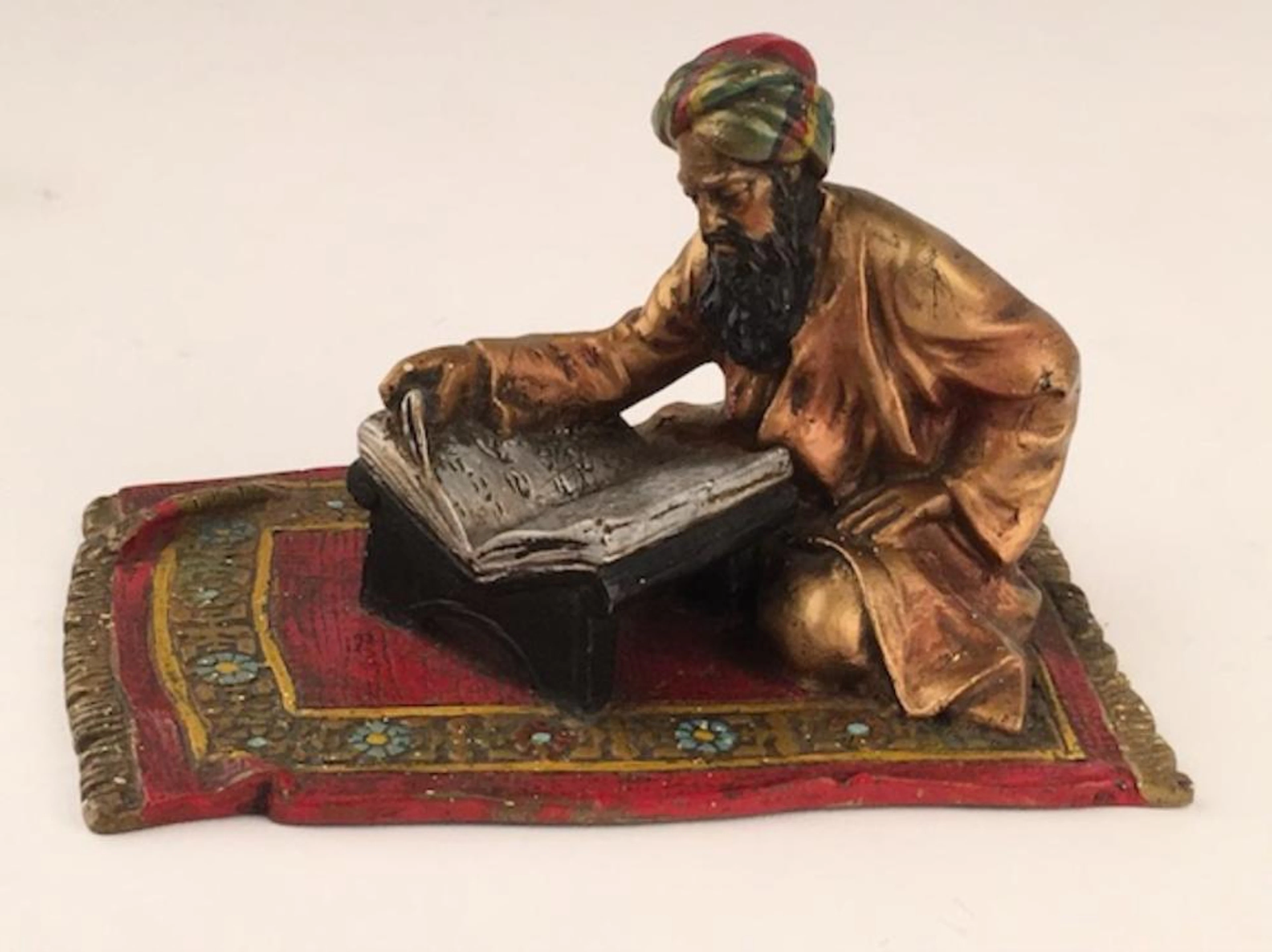 Antique vienna bronze of a man sitting on a carpet reading. Stamped "Austria" o