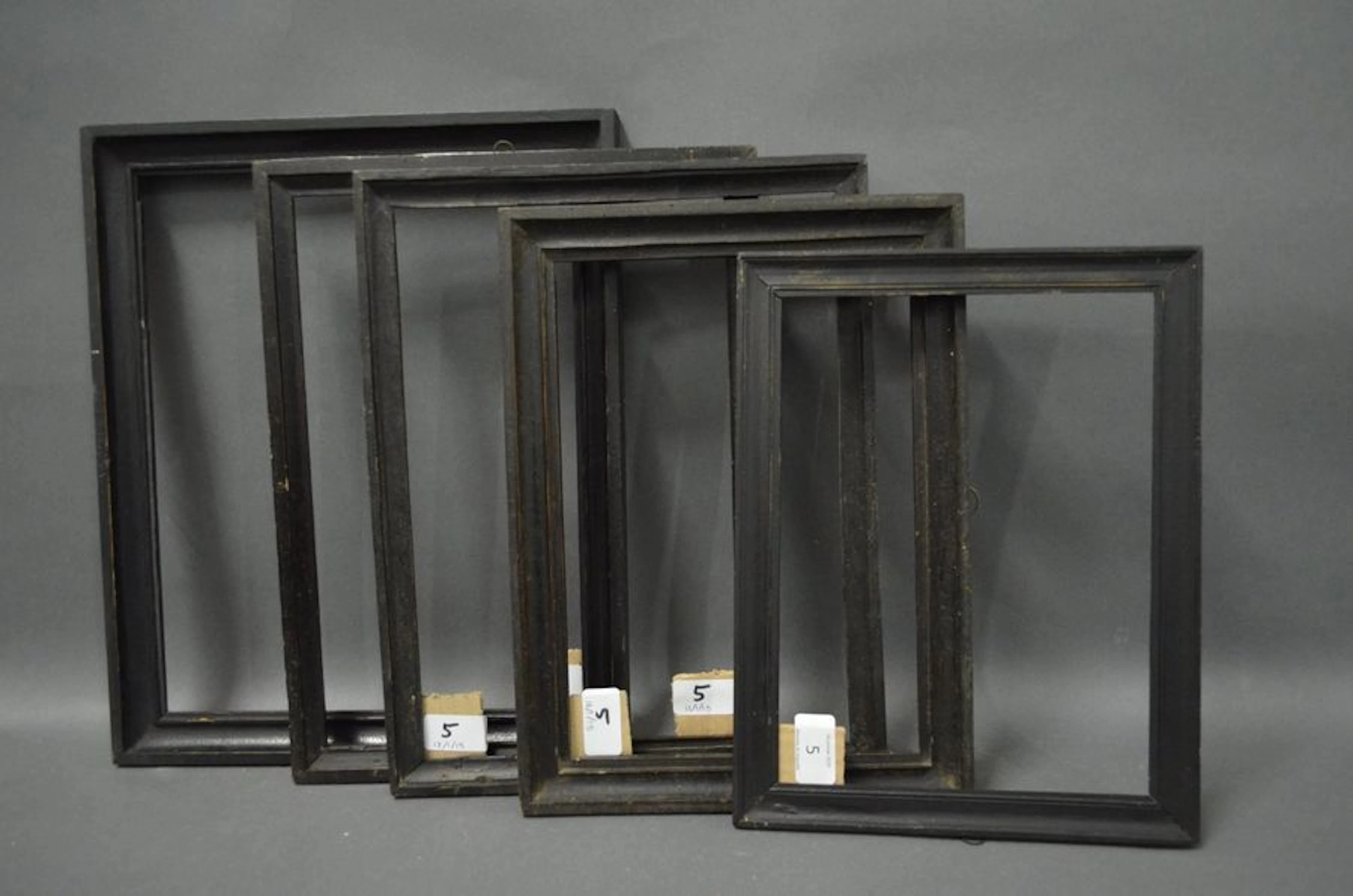 CINQ BAGUETTES en bois mouluré et noirci.…