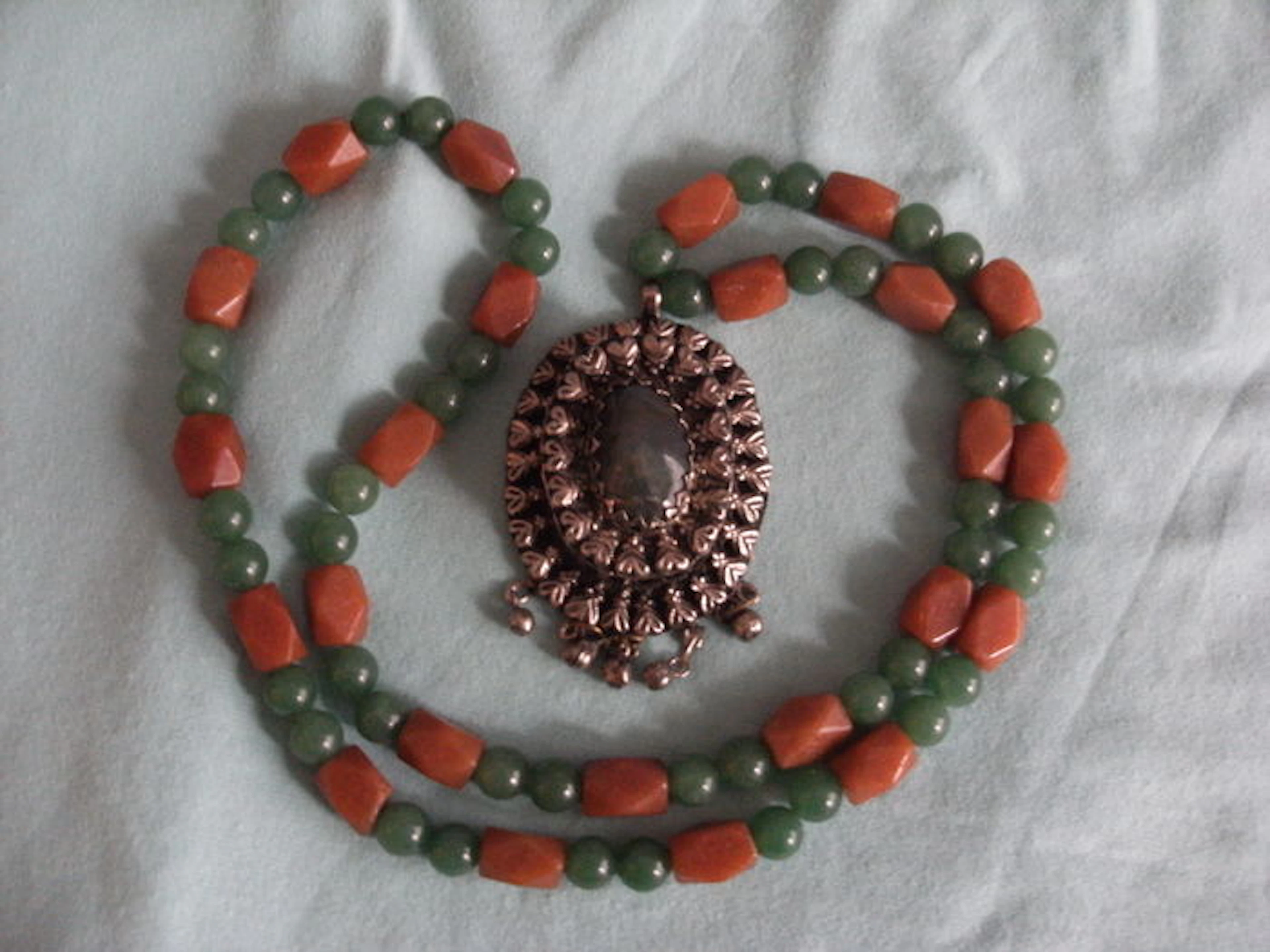 Pendant from the 1960s set with aventurine stone, hanging from a green and red aventurine necklace.
