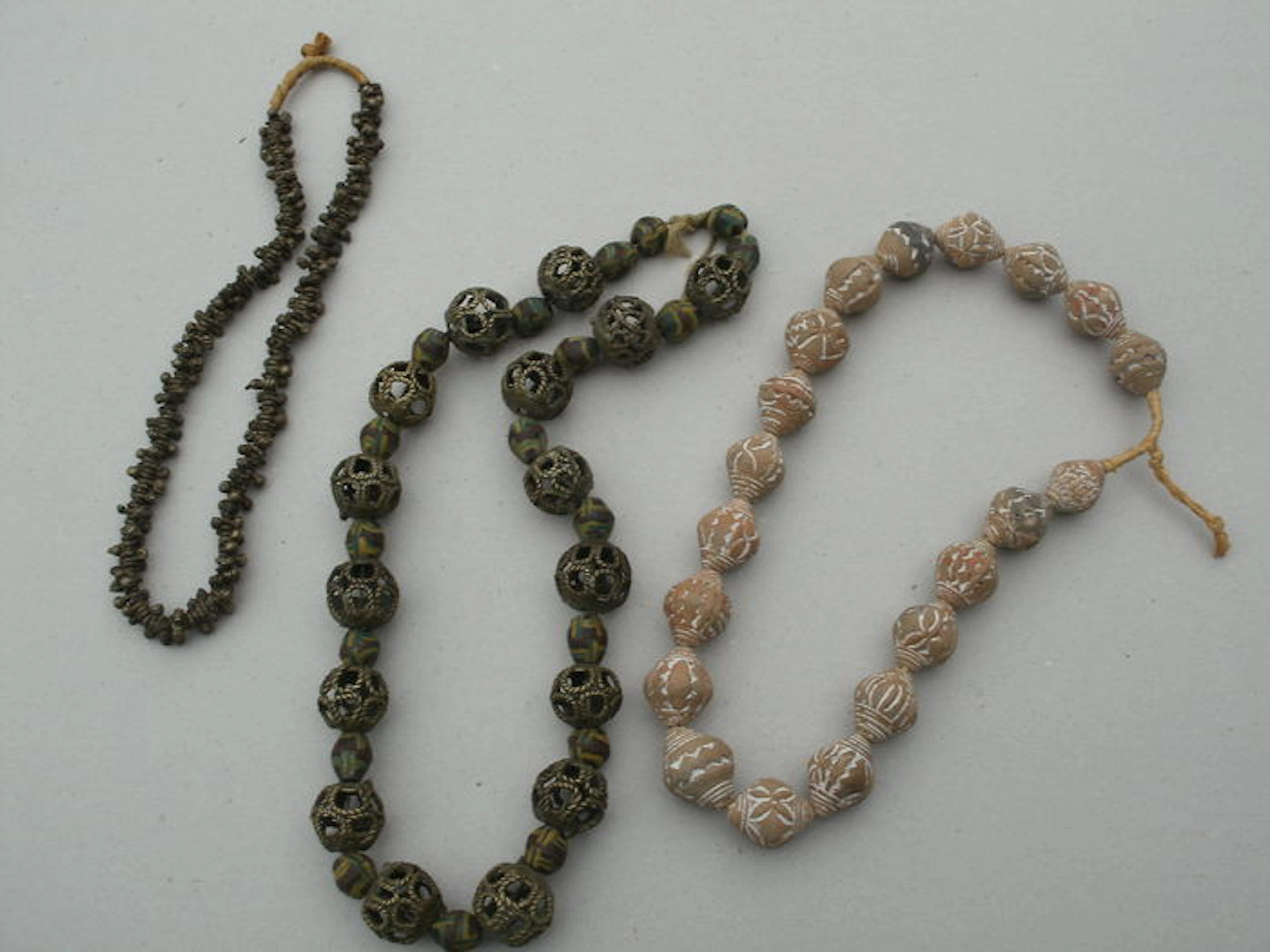Three (bronze / iron / pottery) African necklaces.
