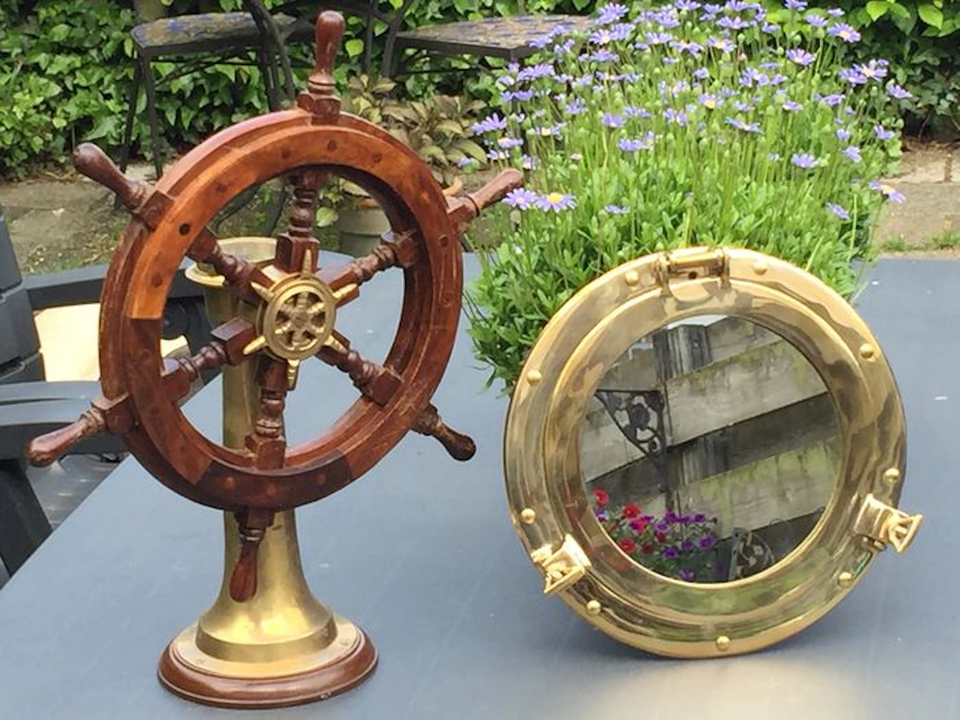 Wooden steering wheel with compass and a brass porthole mirror.