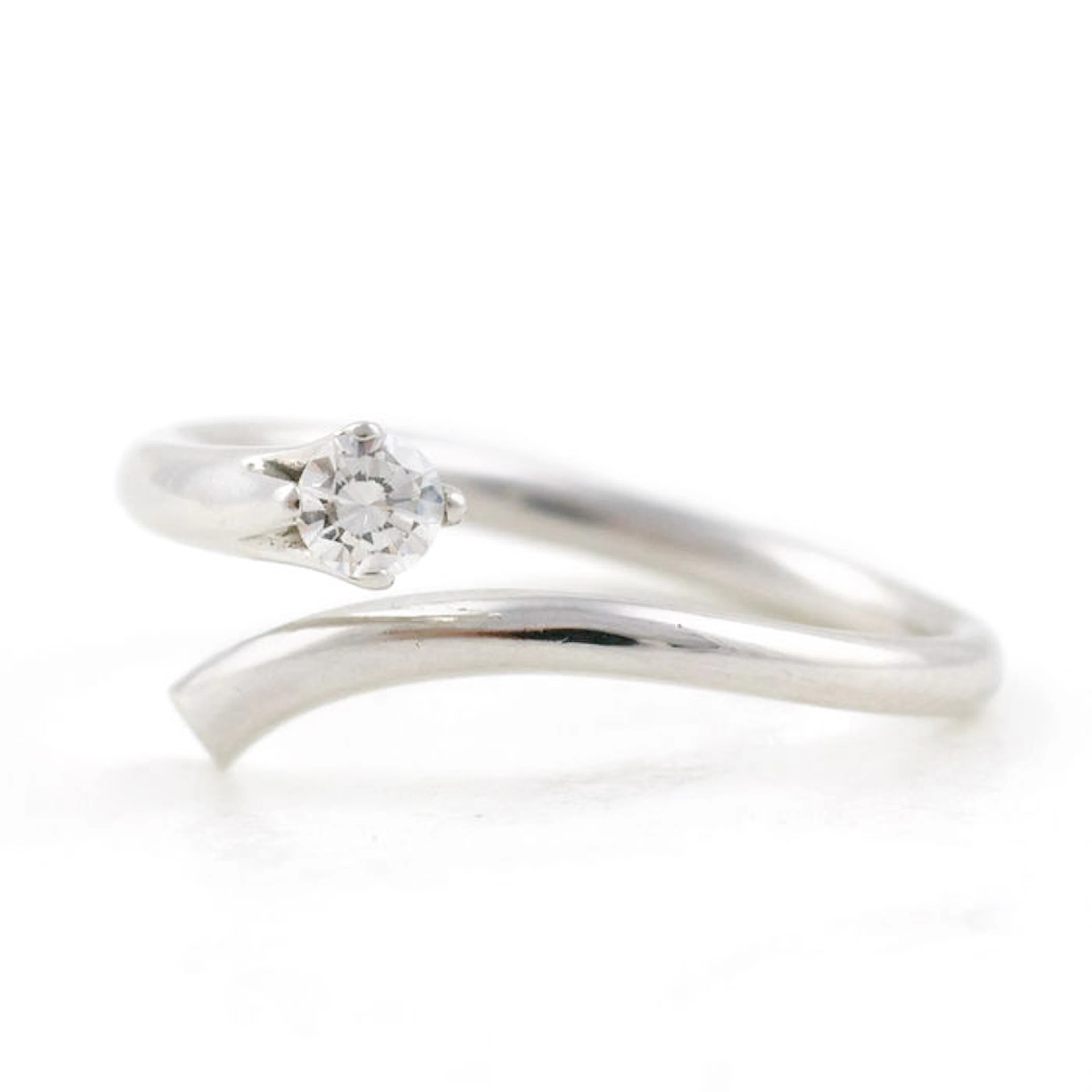 Anillo en oro blanco con brazos en media espiral y diamante solitario en garras