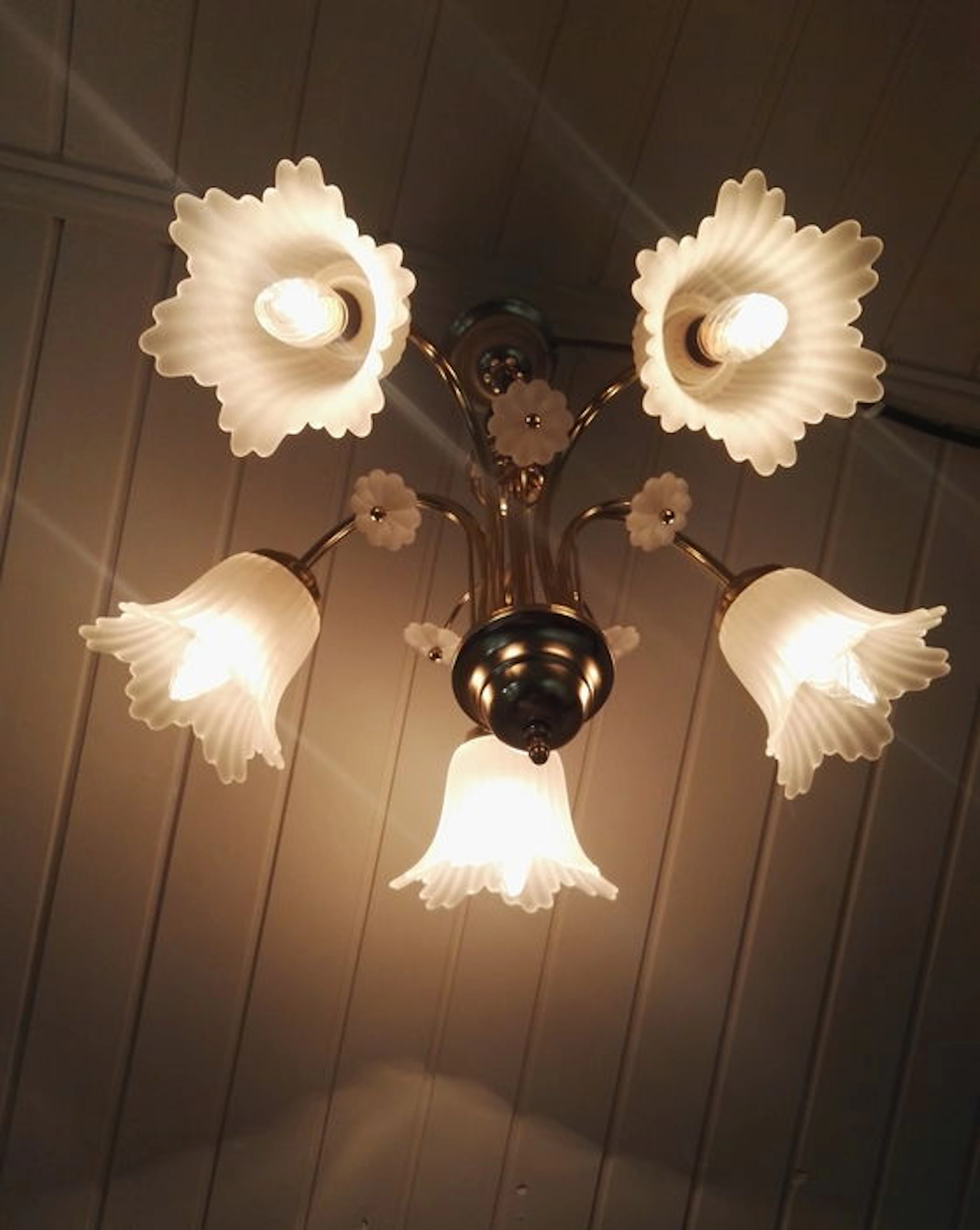 A copper 5-armed chandelier with glass shades and flowers