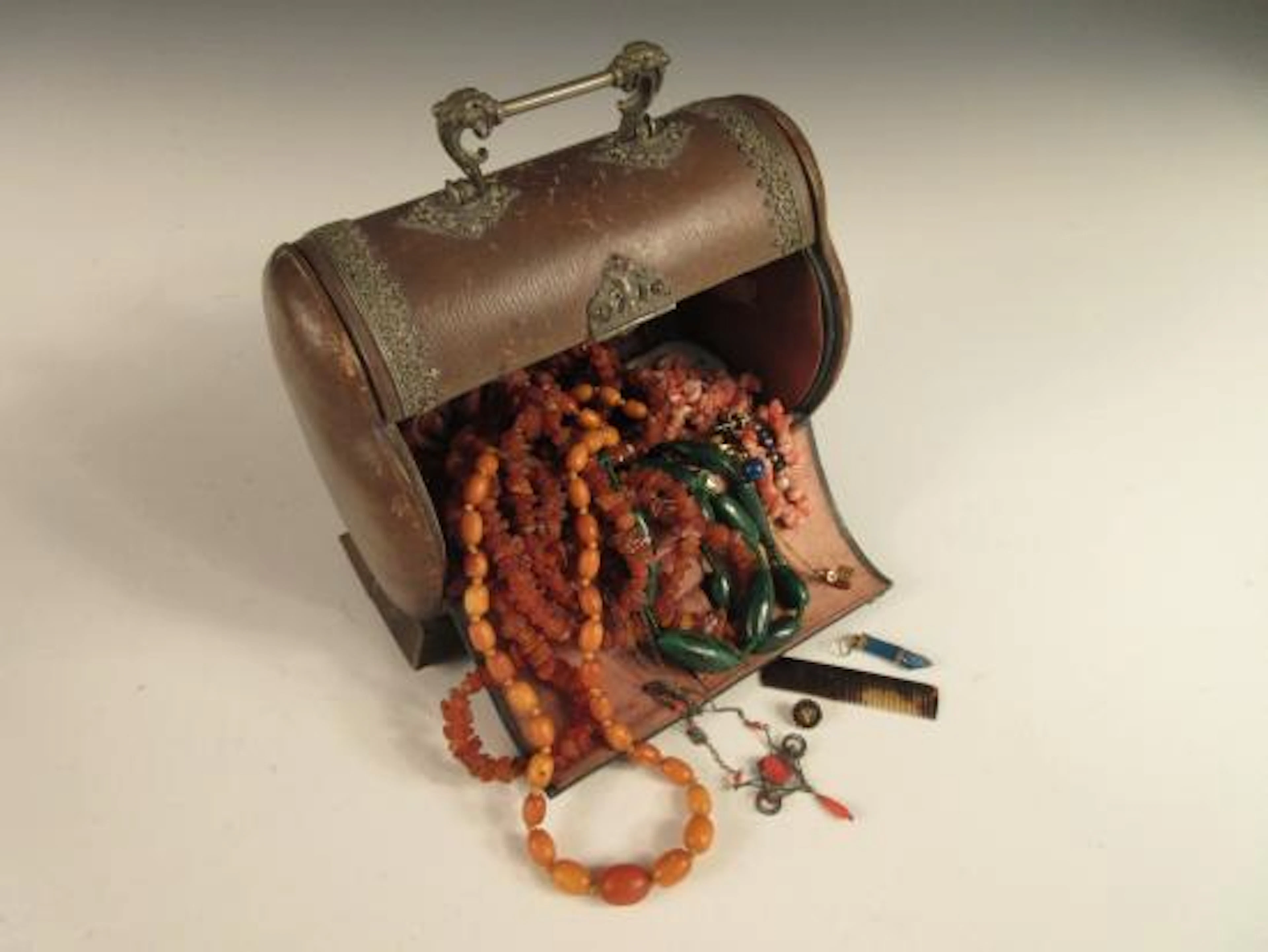 A vintage decorative metal-bound leather jewel casket containing a