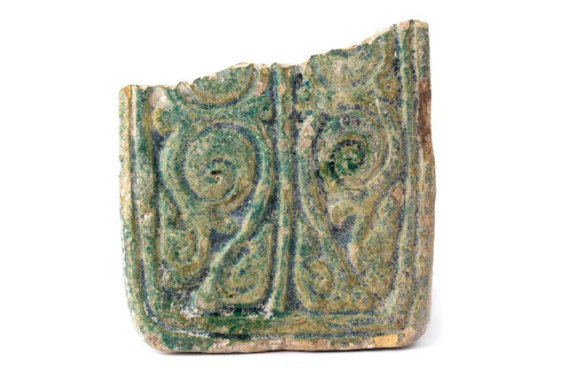 A FRAGMENTARY GREEN-GLAZED POTTERY TILE WITH BIRDS AND VEGETAL ARABESQUE