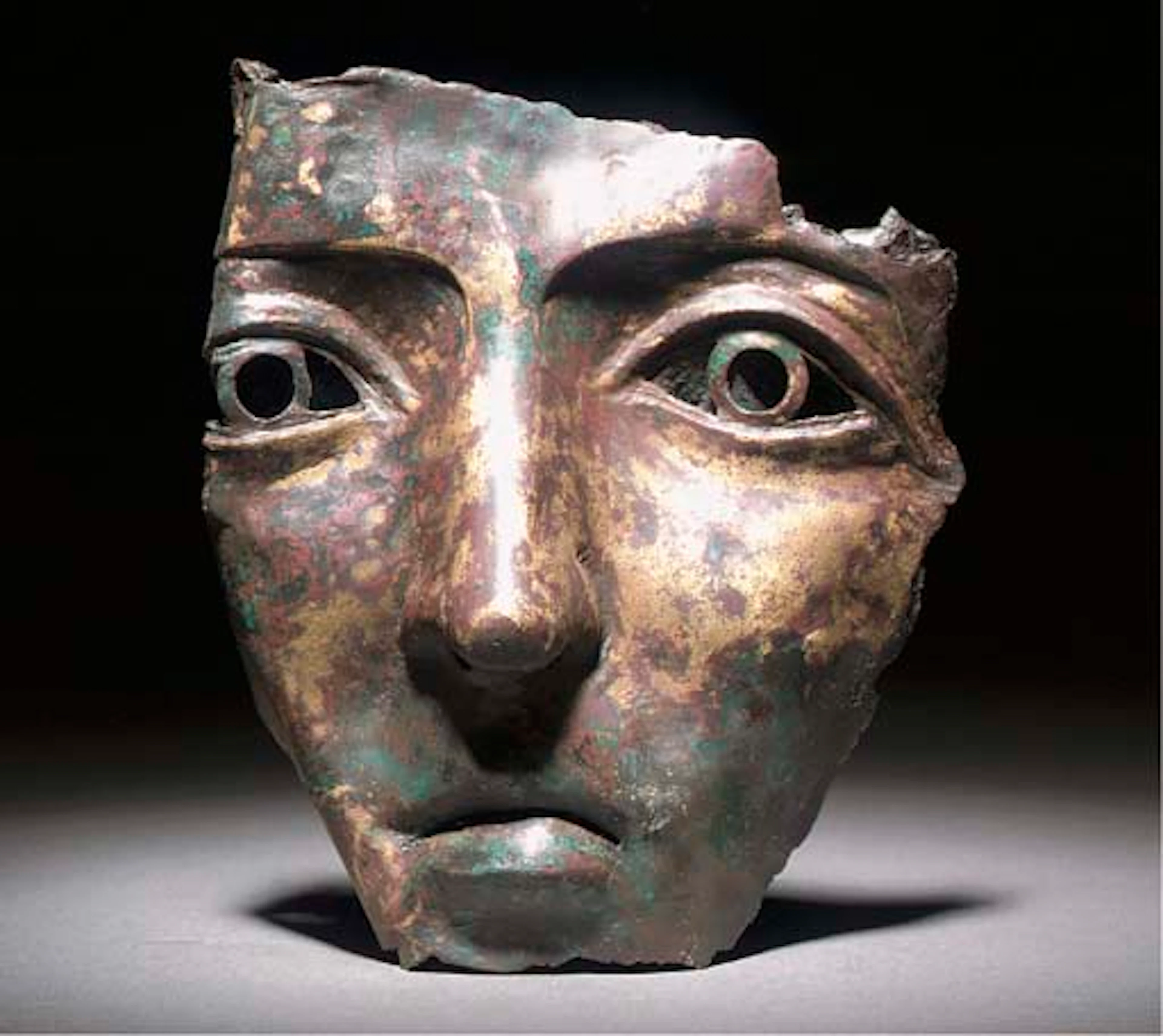 A ROMAN BRONZE ALLOY FRAGMENTARY MASK OF FEMALE TYPE FROM A CAVALRY PARADE HELMET
