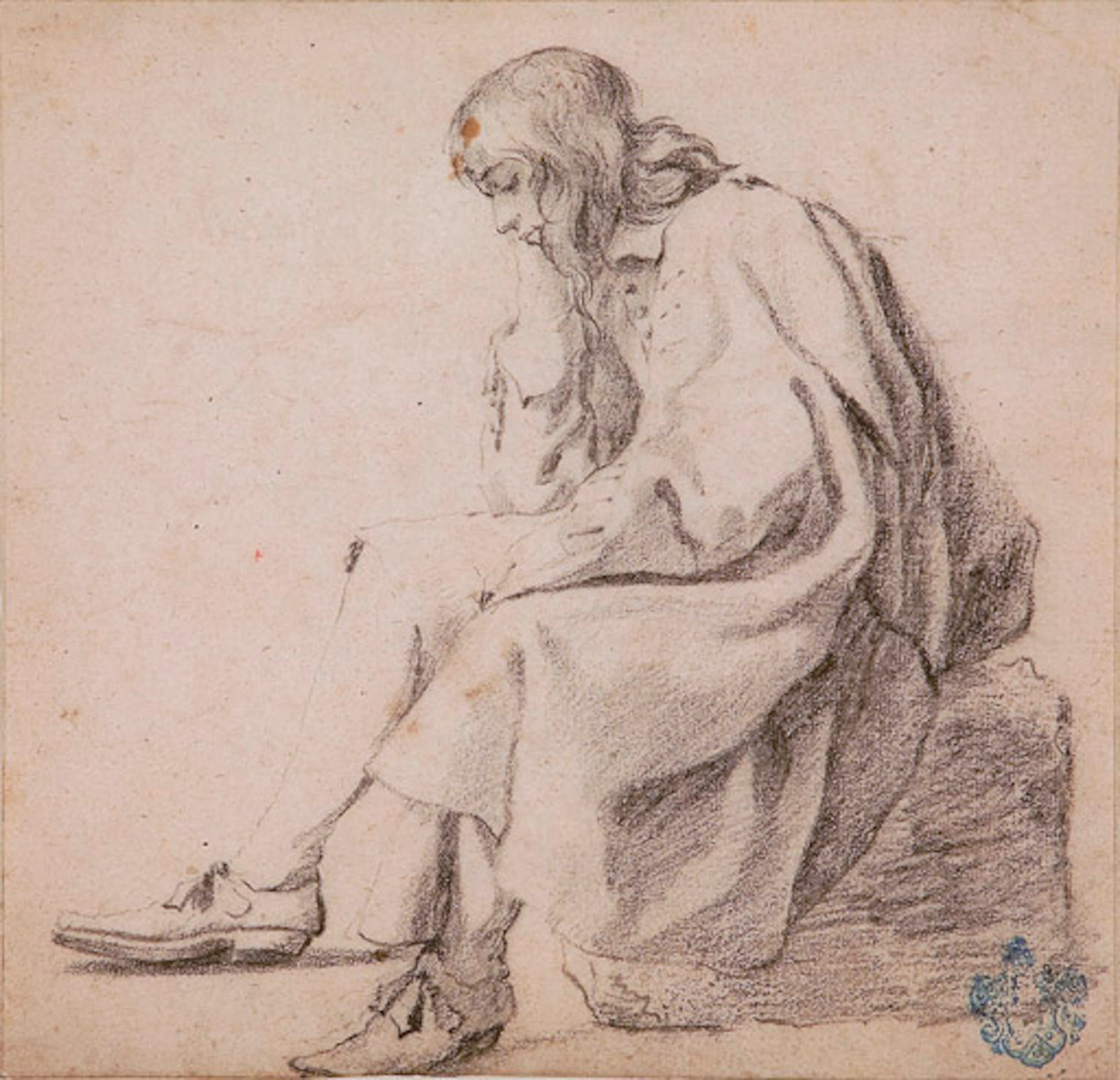 An elegant young man seated on a block resting his head in his right hand