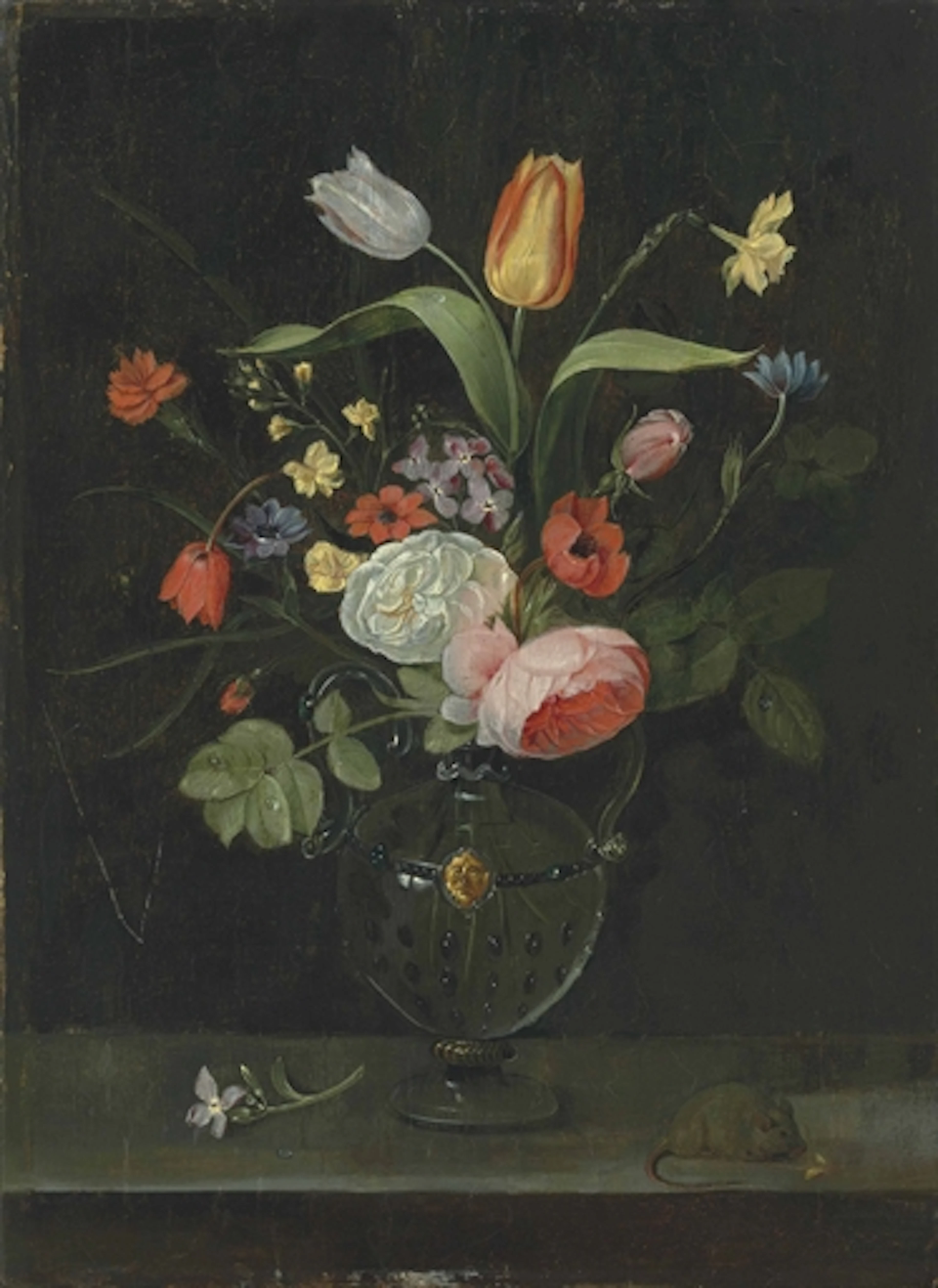 Roses, tulips, a daffodil and other flowers in a glass vase, on a stone ledge with a mouse