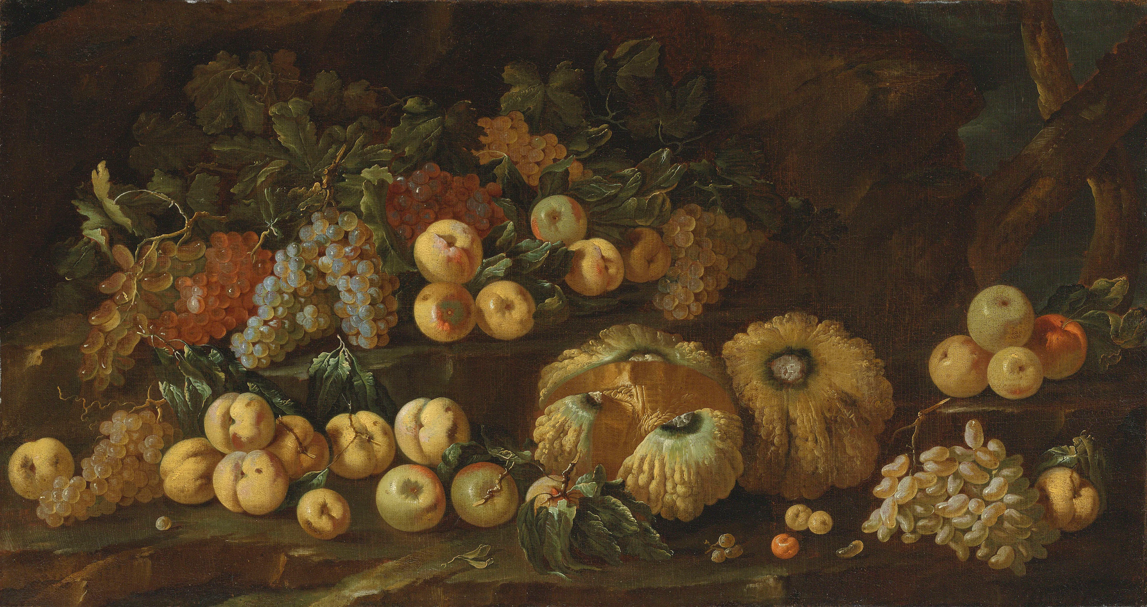 Melons, apples, grapes and other fruit scattered on a rocky ledge
